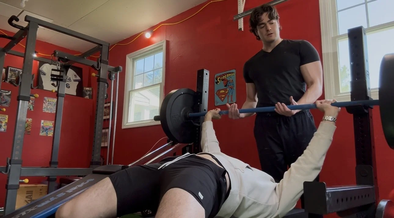 Billy Vetter coaches a client during a bench press workout in his private gym.