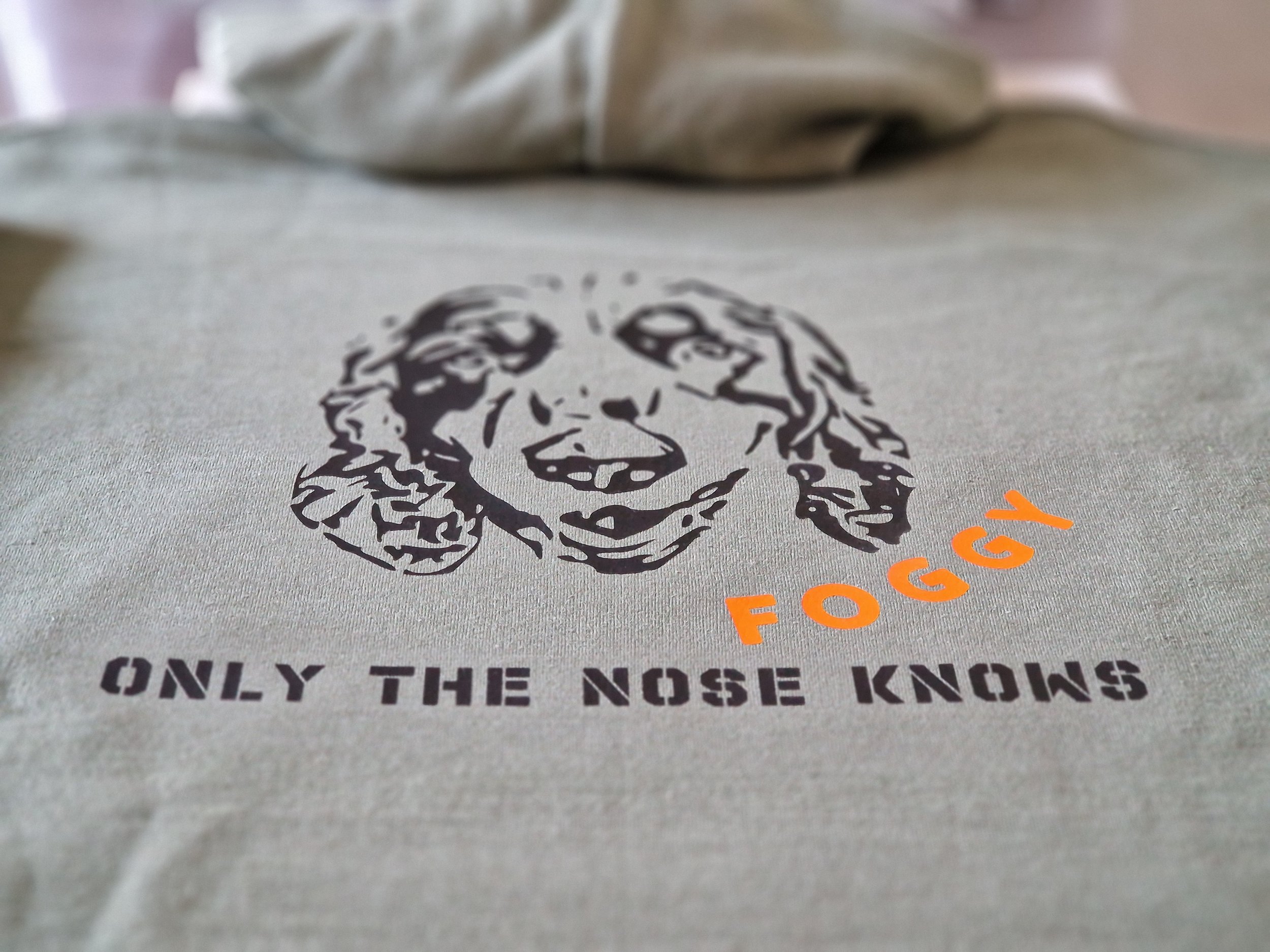 Close-up of a printed message on fabric that reads 'ONLY THE NOSE KNOWS' with a graphic of a dog's face above the text.