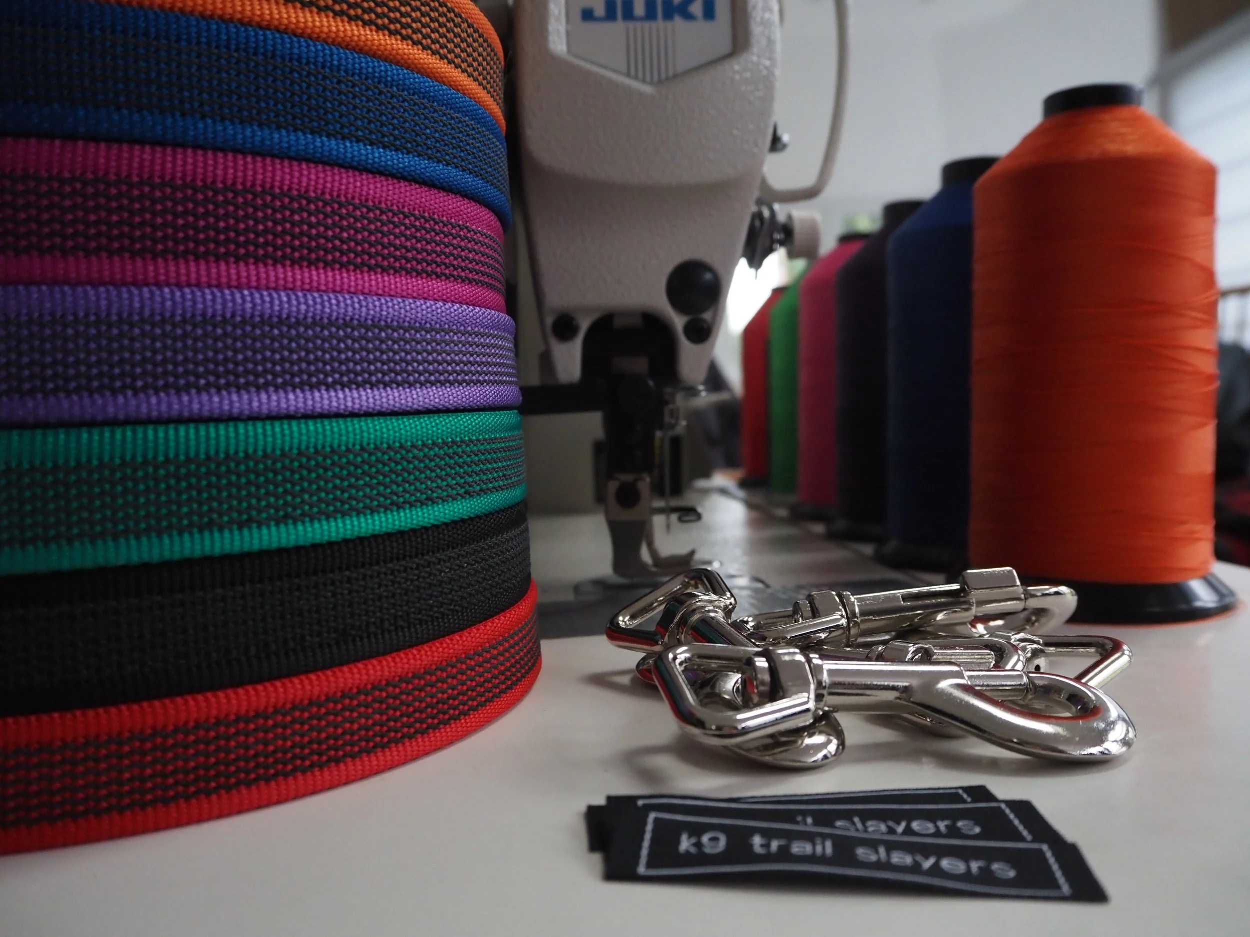 Close-up view of colorful roll tips with embroidery, sewing machine, and metal clips on a white surface.