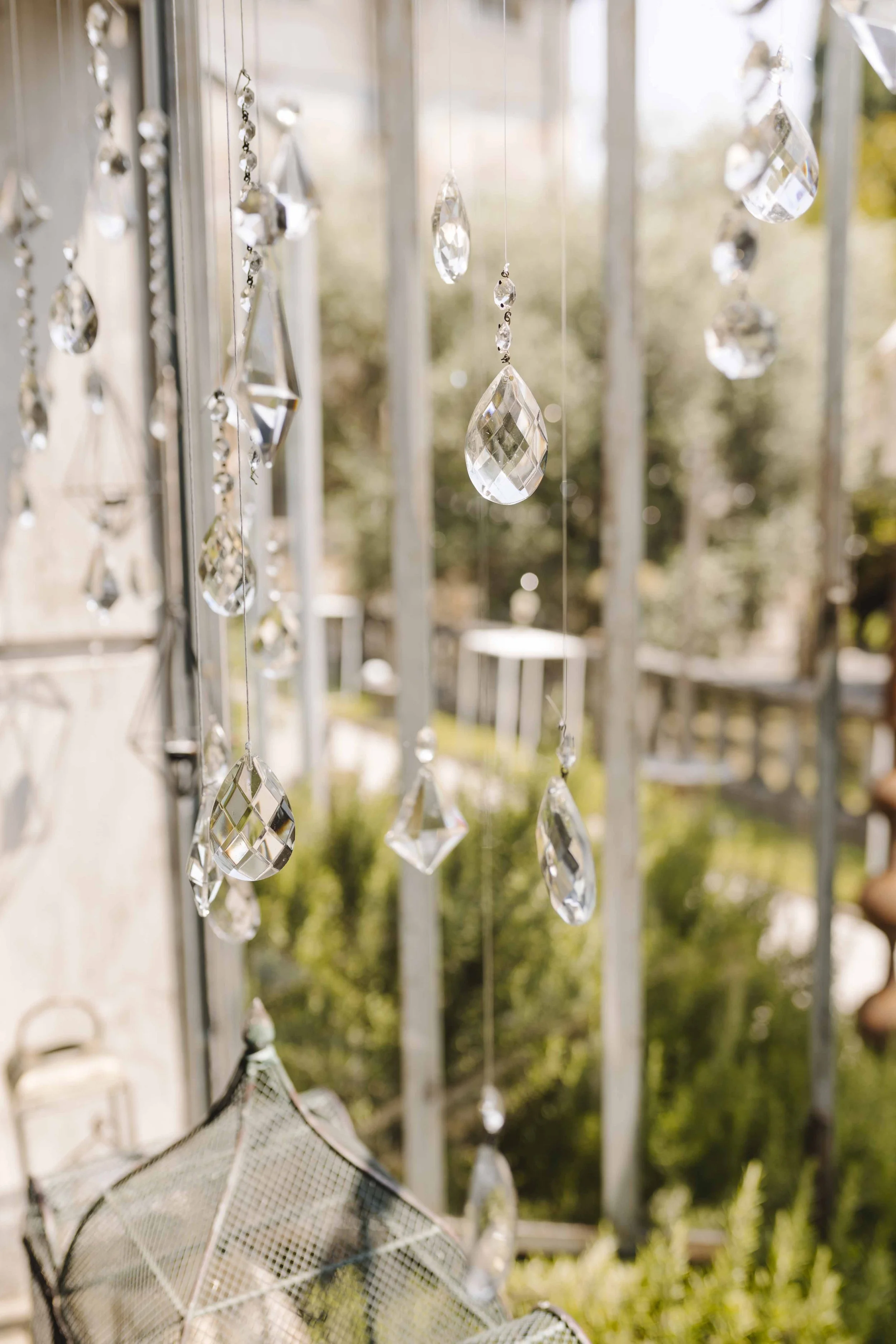 Close-up of hanging crystal decorations in sunlight with a blurred outdoor background.