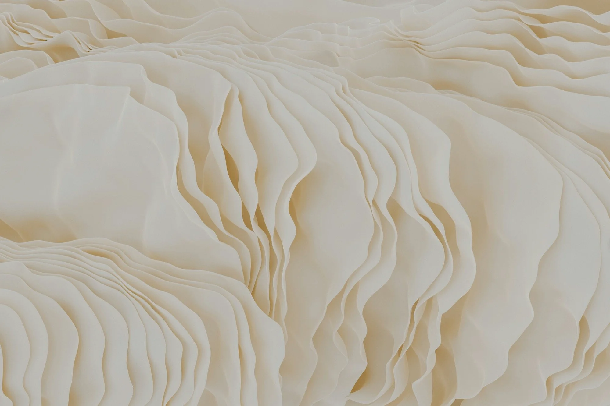Close-up of layered, cream-colored paper or fabric with wavy, undulating patterns.