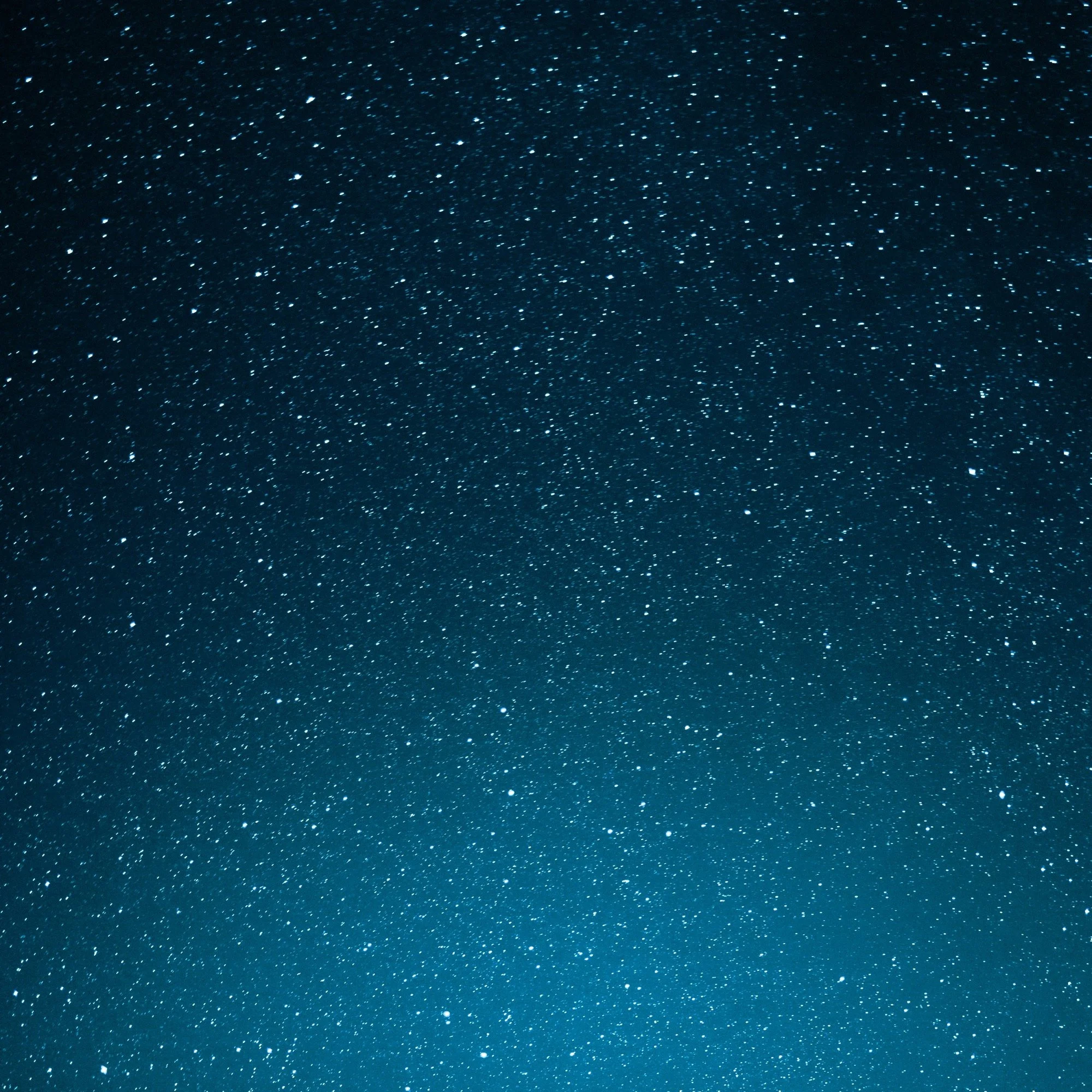 A starry night sky with numerous tiny white stars scattered across a dark blue background.