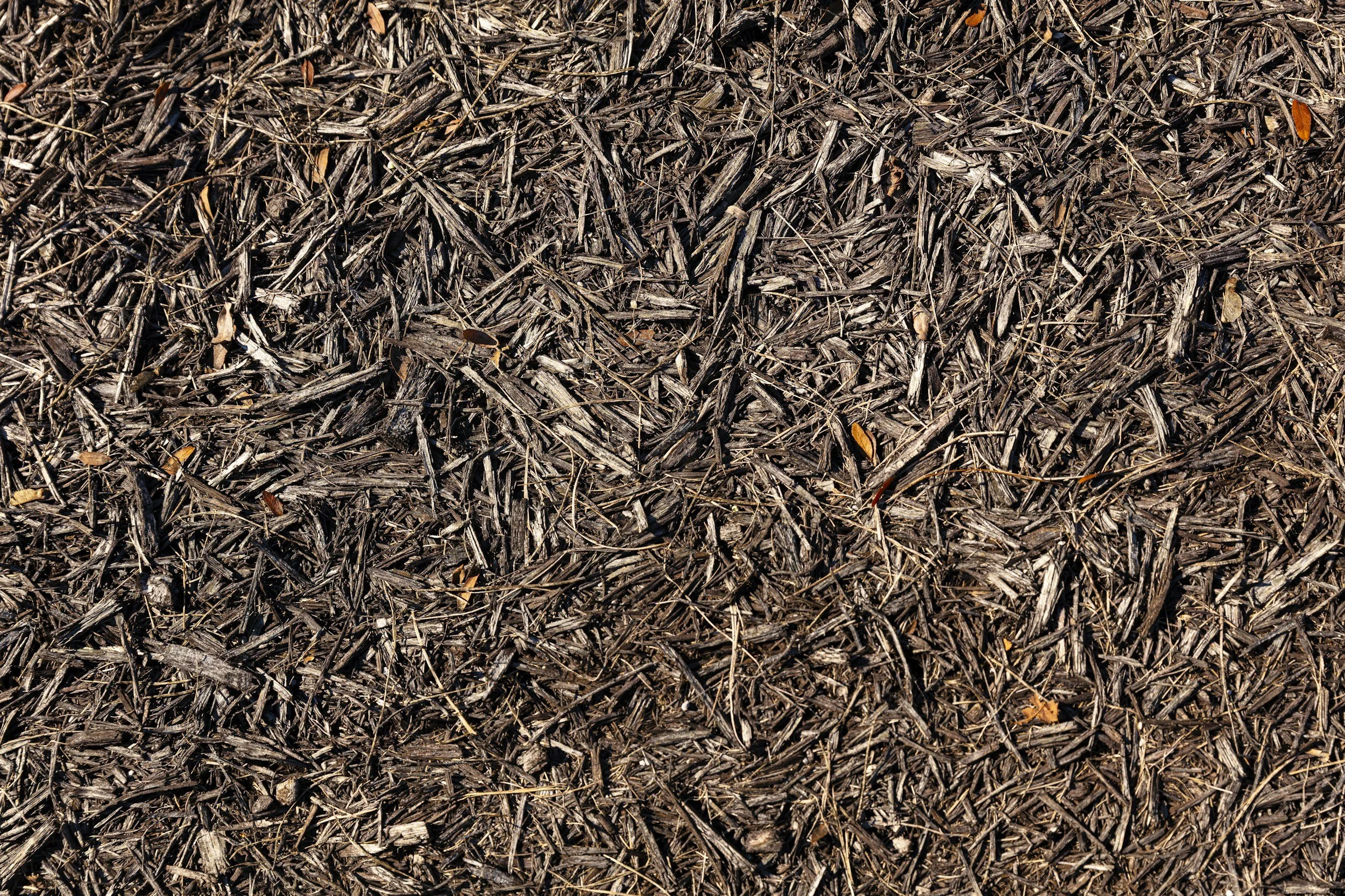Close-up photograph of a dense layer of brown mulch composed of small wood chips and twigs.