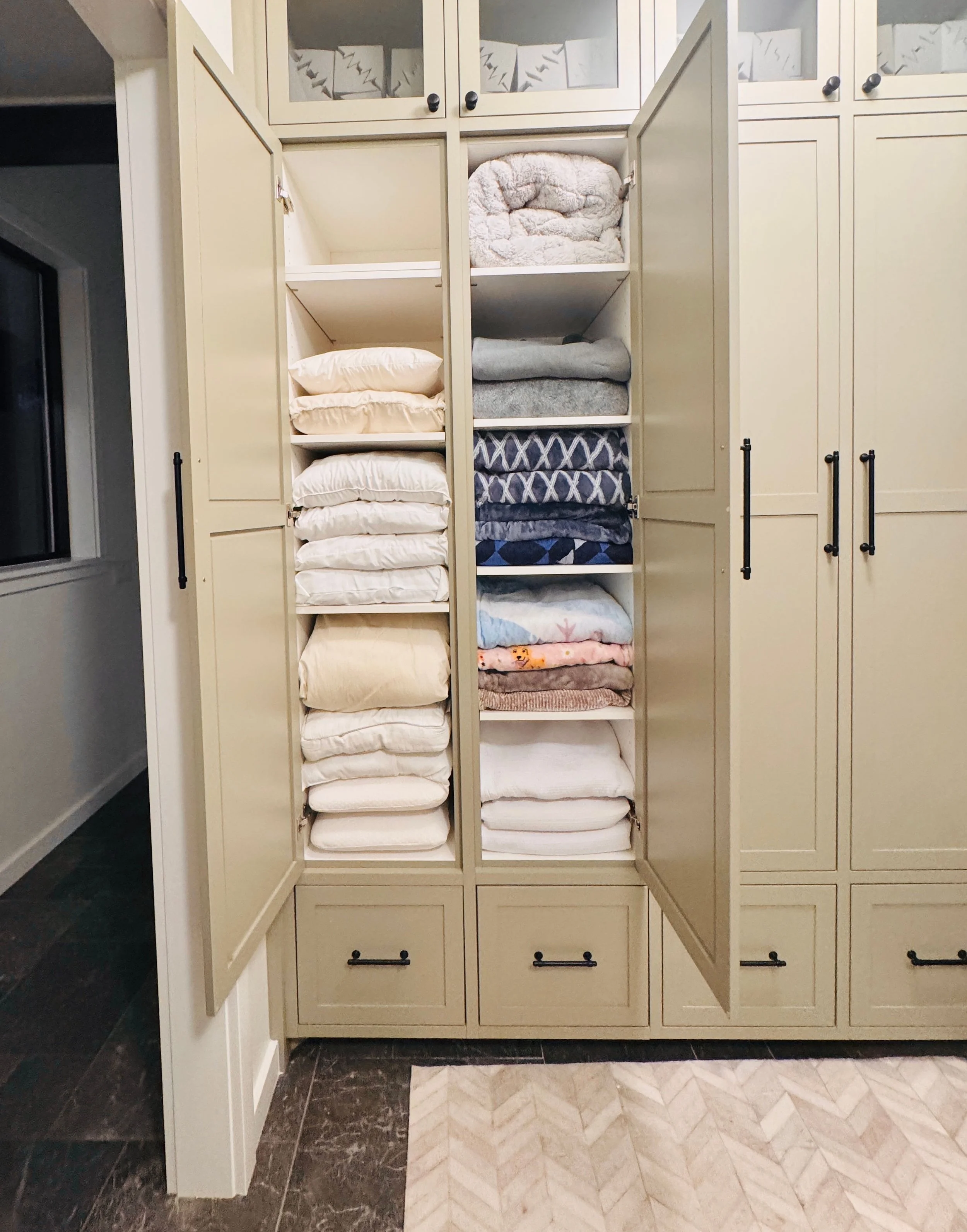 Deep laundry room cabinet organization featuring neatly stacked blankets, pillows, and extra linens in Park City, Utah.