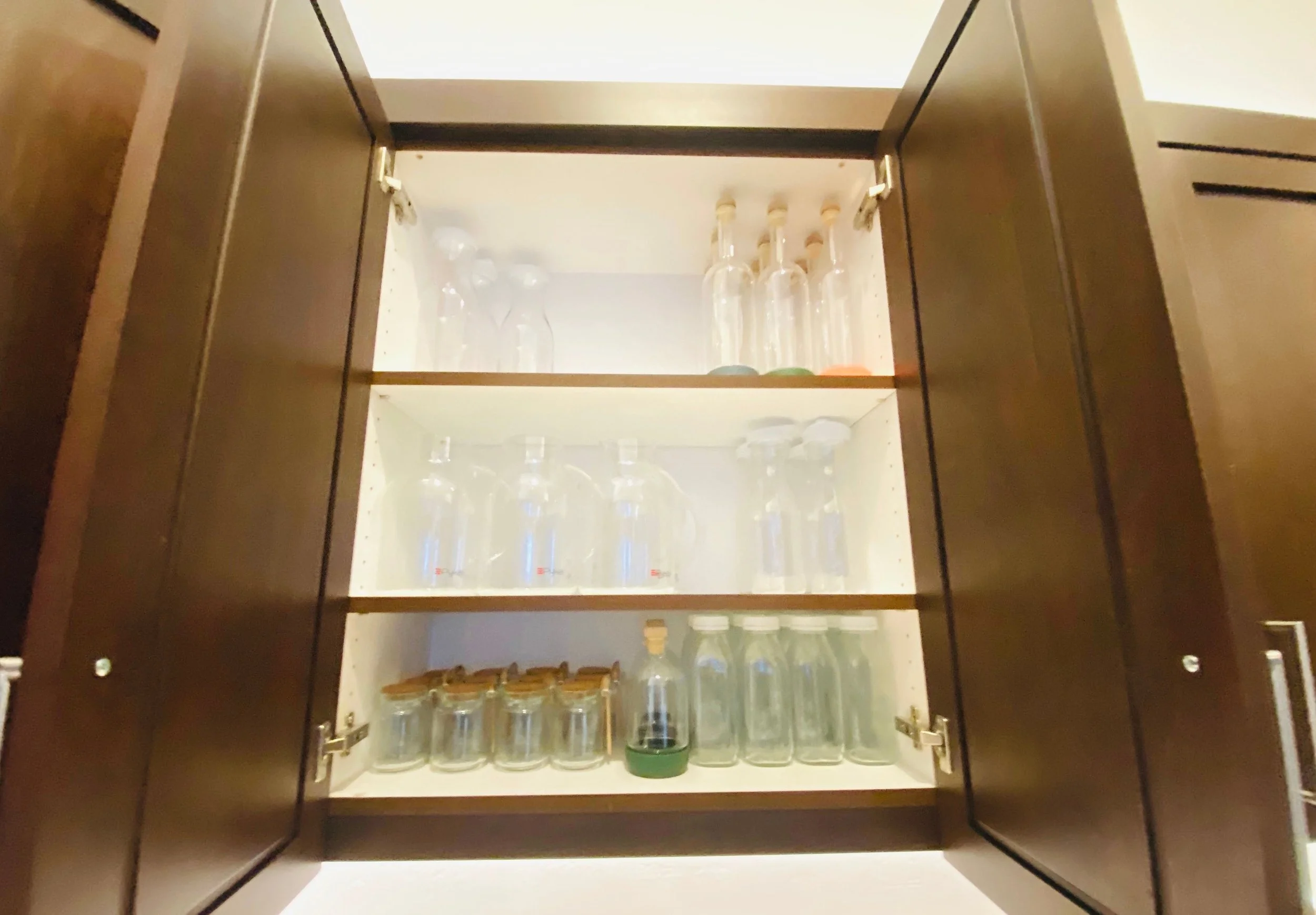 Elegantly organized party supply cabinet featuring a wide selection of serving containers, pitchers, and carafes for entertaining in Park City, Utah.