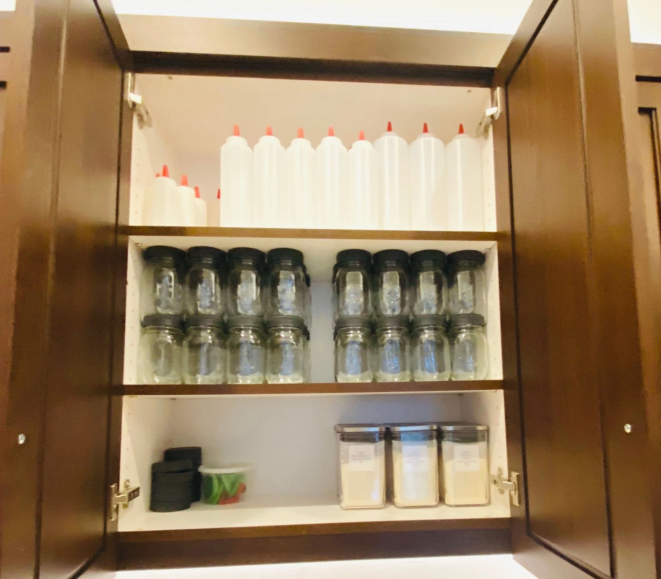 Professional chef kitchen cabinet organization featuring neatly arranged Ball jars, squeeze bottles, and culinary prep supplies in Park City, Utah.