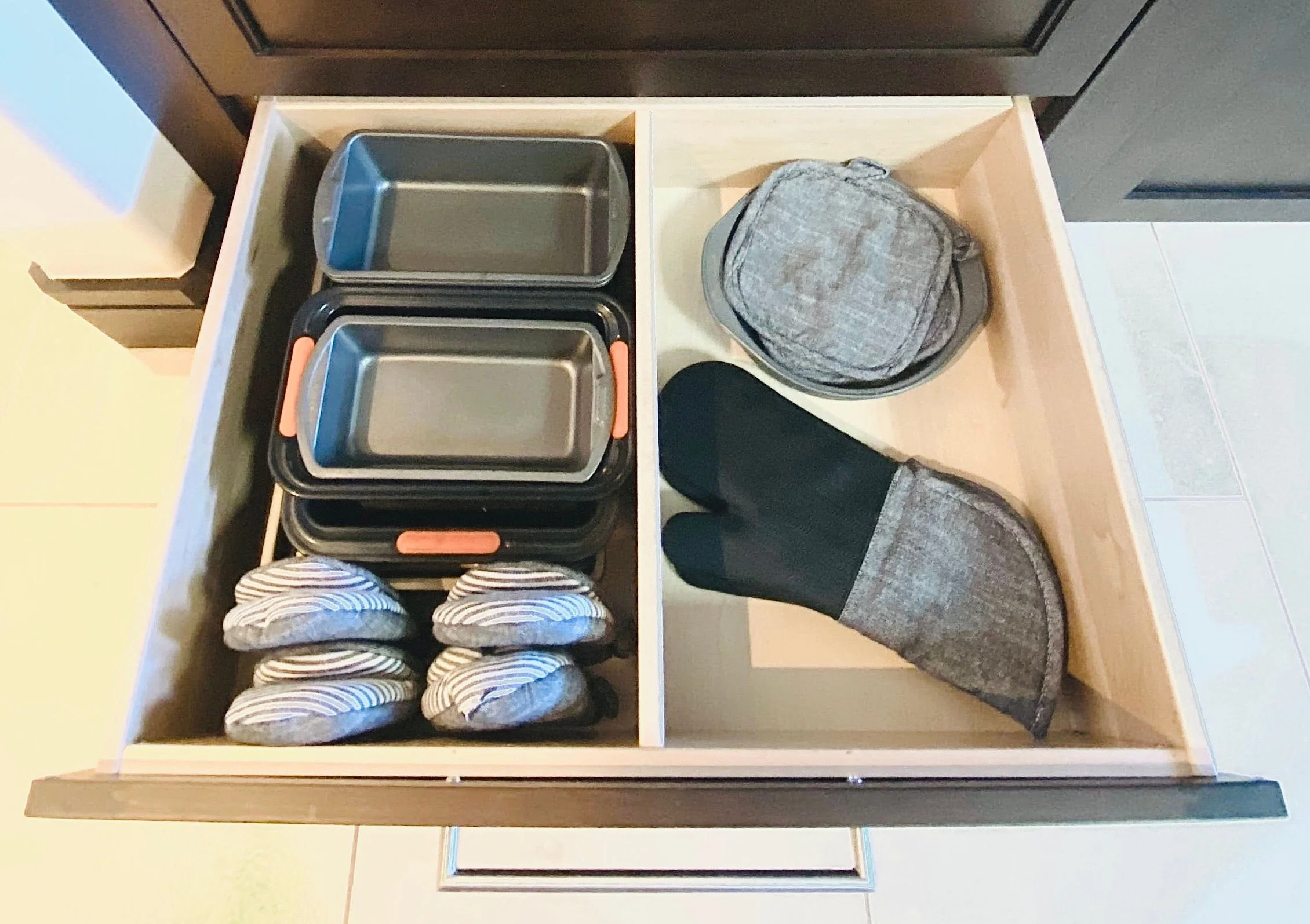 Functional kitchen drawer organization featuring neatly arranged baking pans, cookie sheets, and matching oven mitts in Park City, Utah.