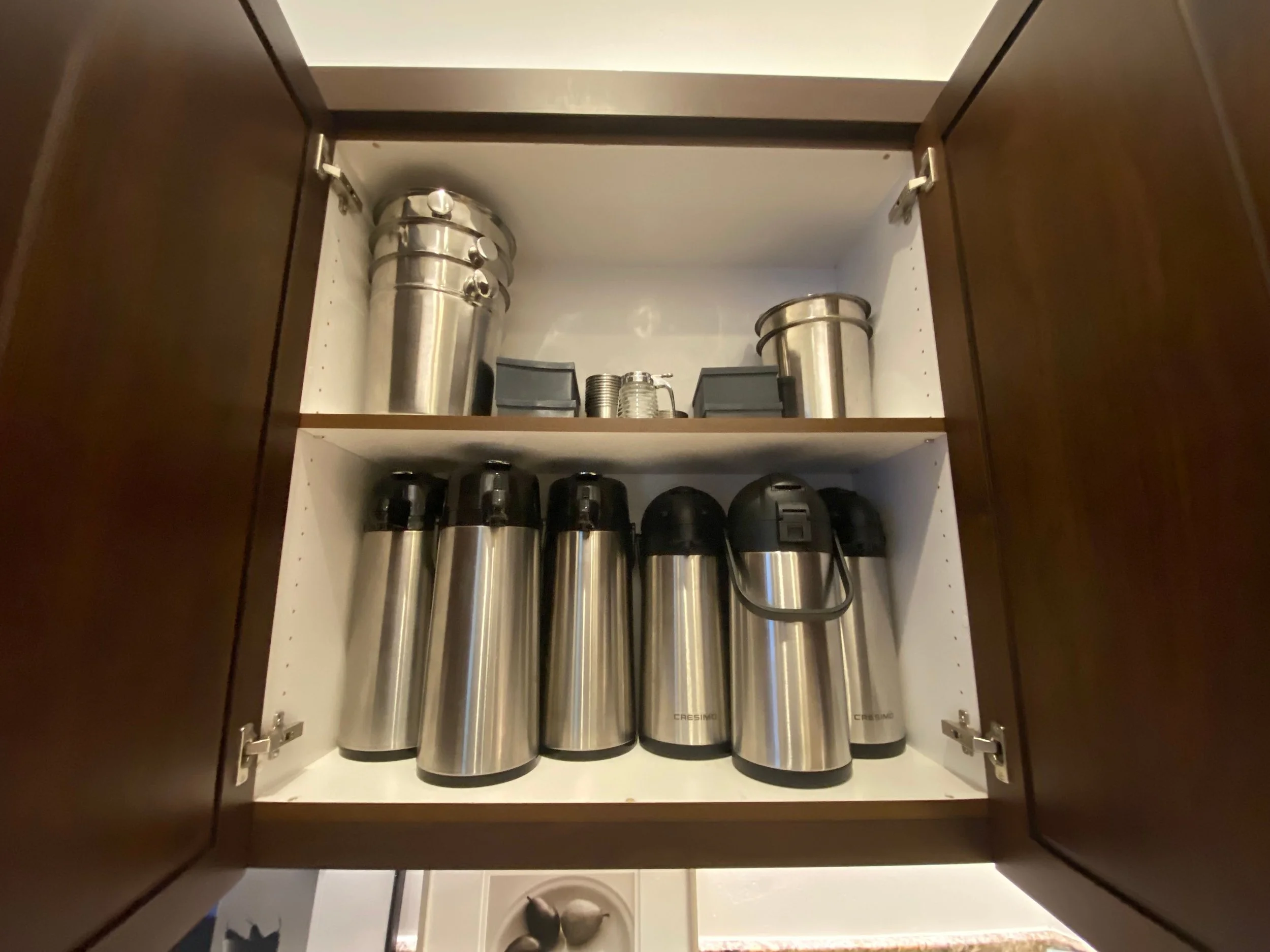 Specialized kitchen cabinet organization featuring neatly stored coffee carafes, thermal pitchers, and party ice bins for entertaining in Park City, Utah.