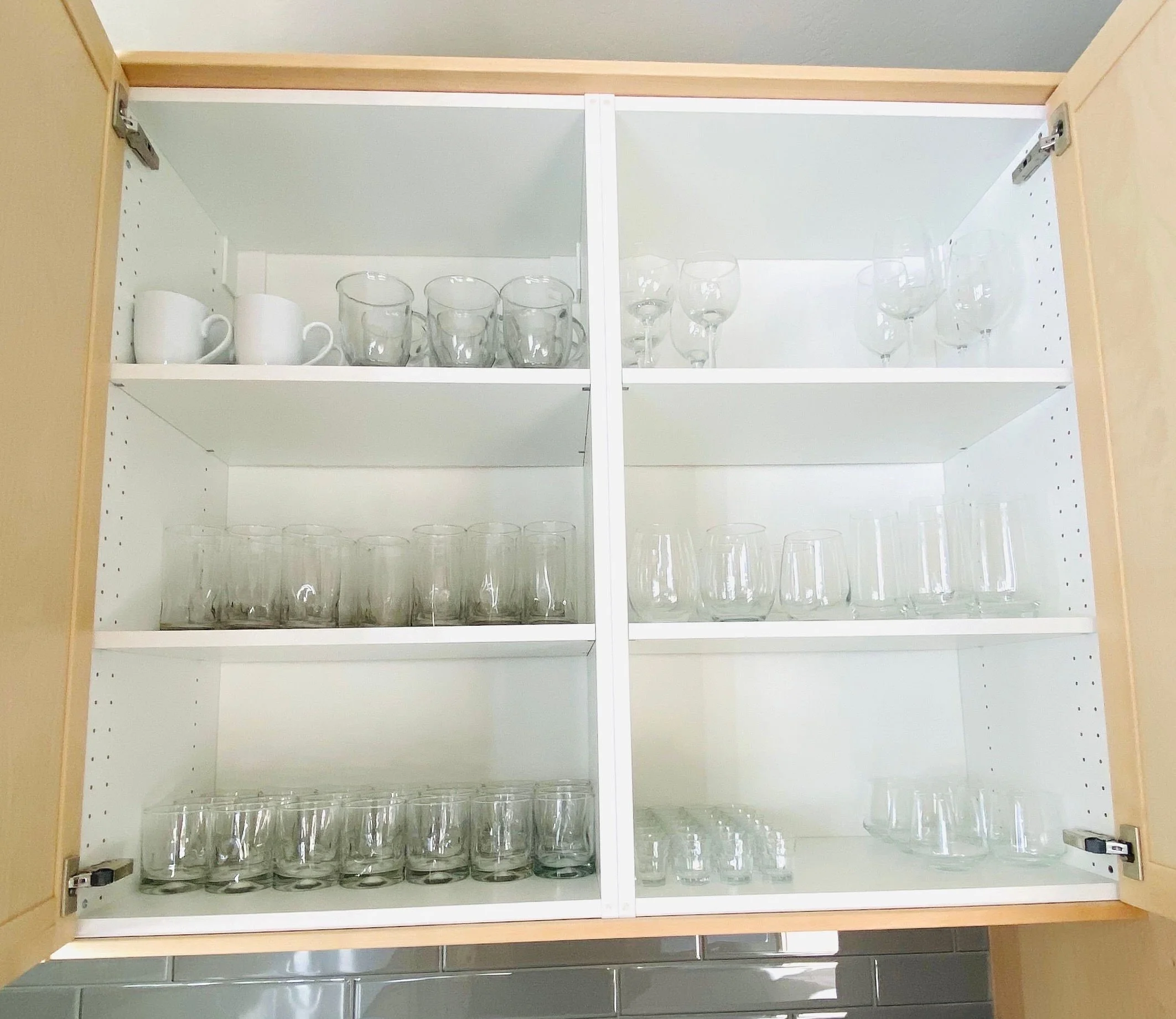 Beautiful kitchen cabinet organization displaying cute mugs, matching cups, and styled wine and champagne glasses in Park City, Utah.