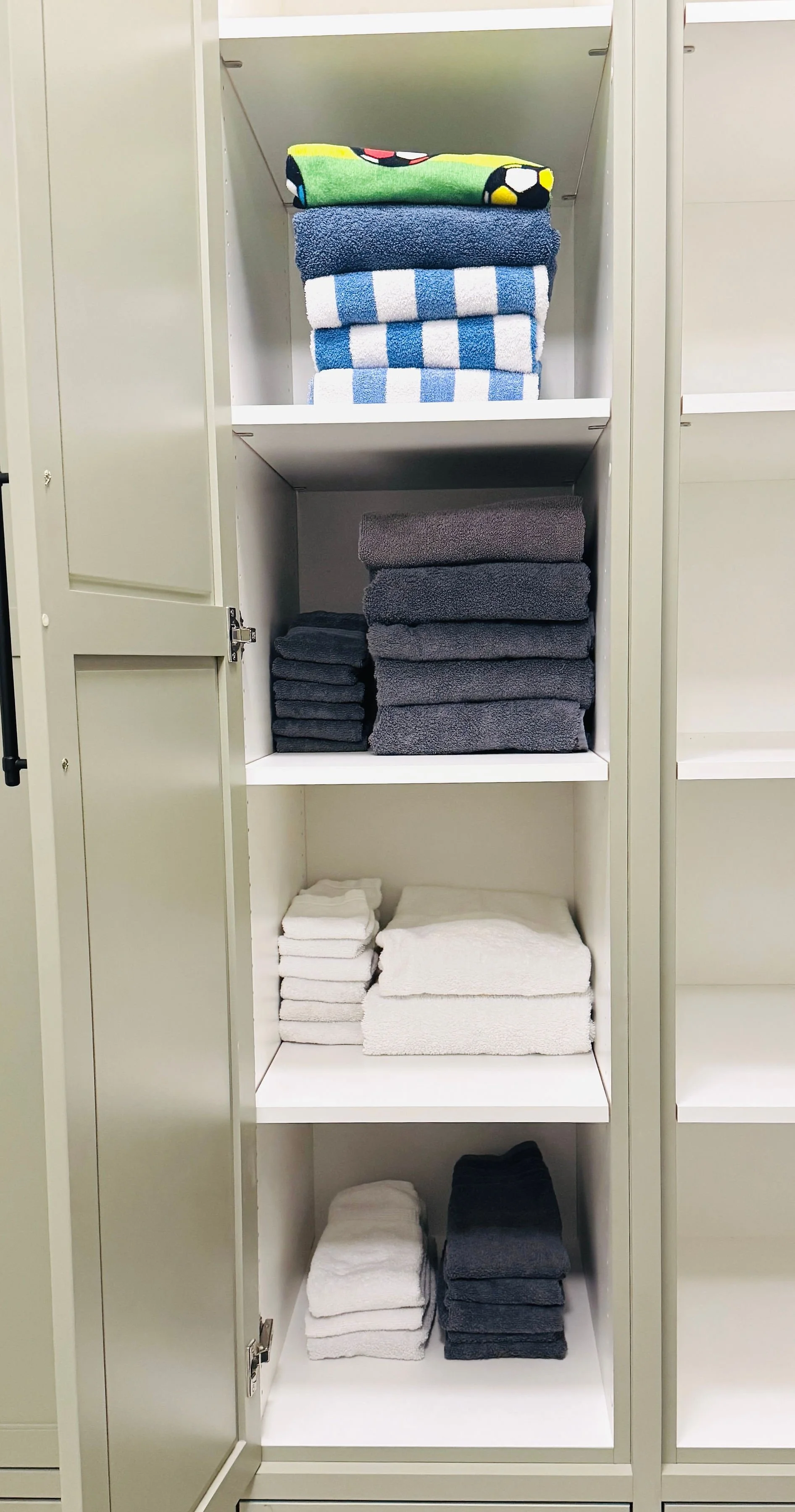 Beautifully organized linen closet featuring neatly folded resort-style pool towels, bath towels, hand towels, and face cloths in Park City, Utah.