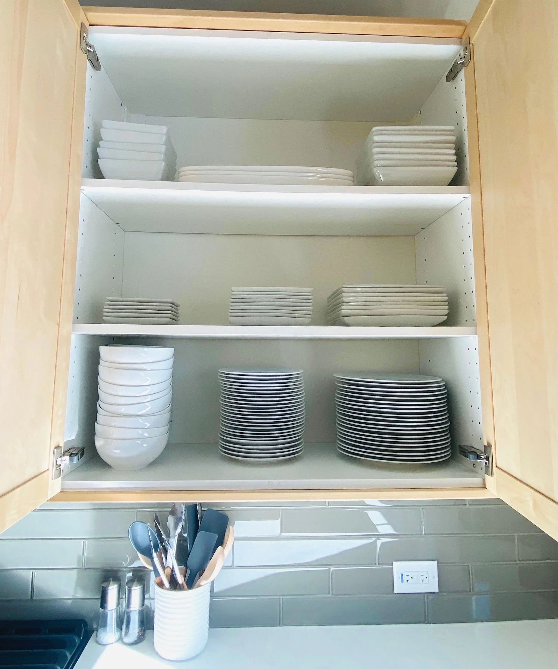 Functional kitchen cabinet organization featuring neatly stacked plates, bowls, and dinnerware storage systems in Park City, Utah.