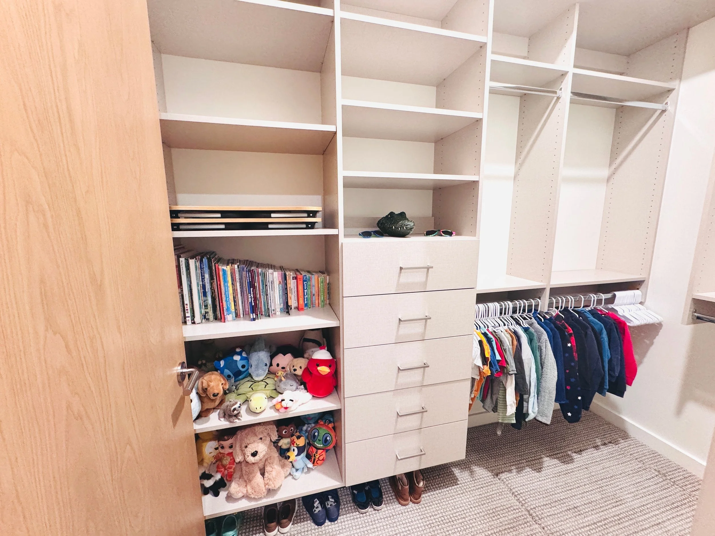 Custom little boys' walk-in closet organization featuring designated zones for clothing, books, and stuffed animal storage in Park City, Utah.