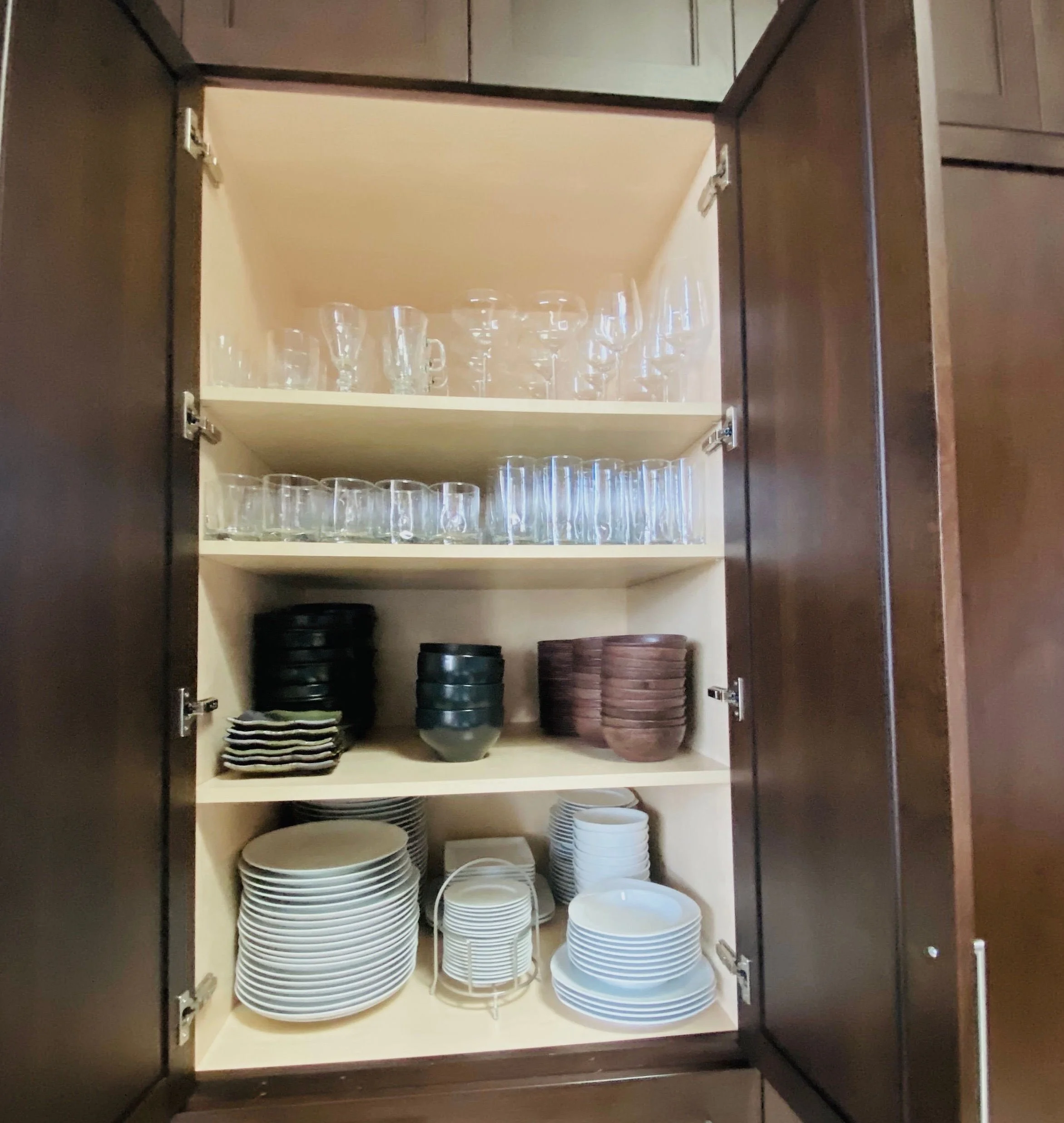 Organized kitchen cabinet featuring a curated variety of casual and fine dining plates, bowls, and matching cups in Park City, Utah.