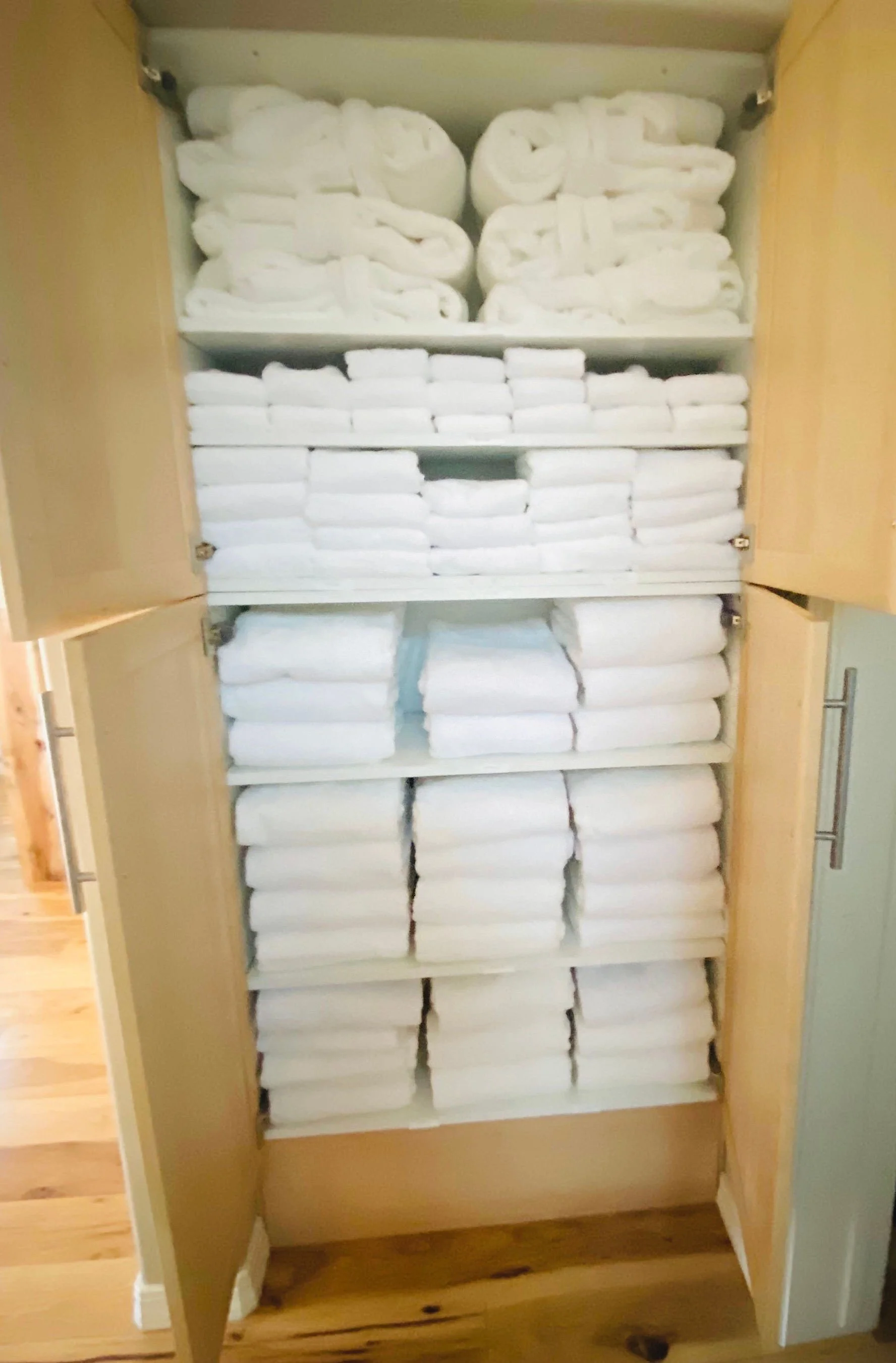Luxury guest bedroom closet organization featuring fully stocked, premium bath towels of all sizes and robes in a Park City, Utah residence.