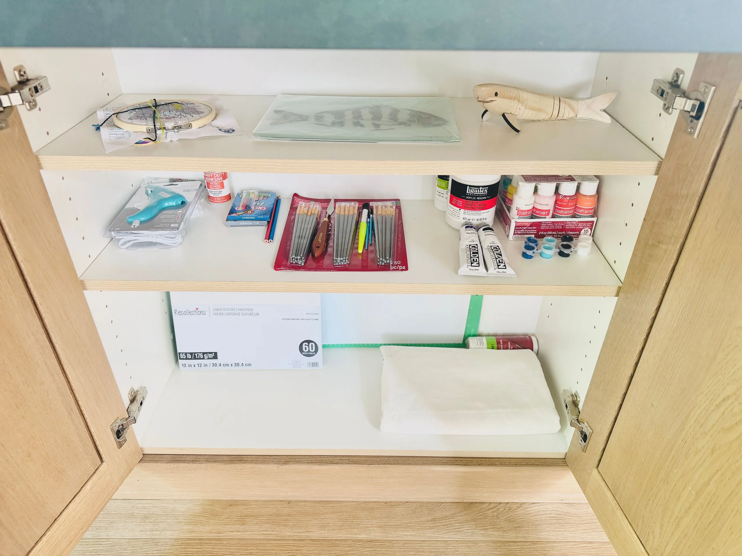 Streamlined art supply organization using cabinet storage for a Park City home studio.