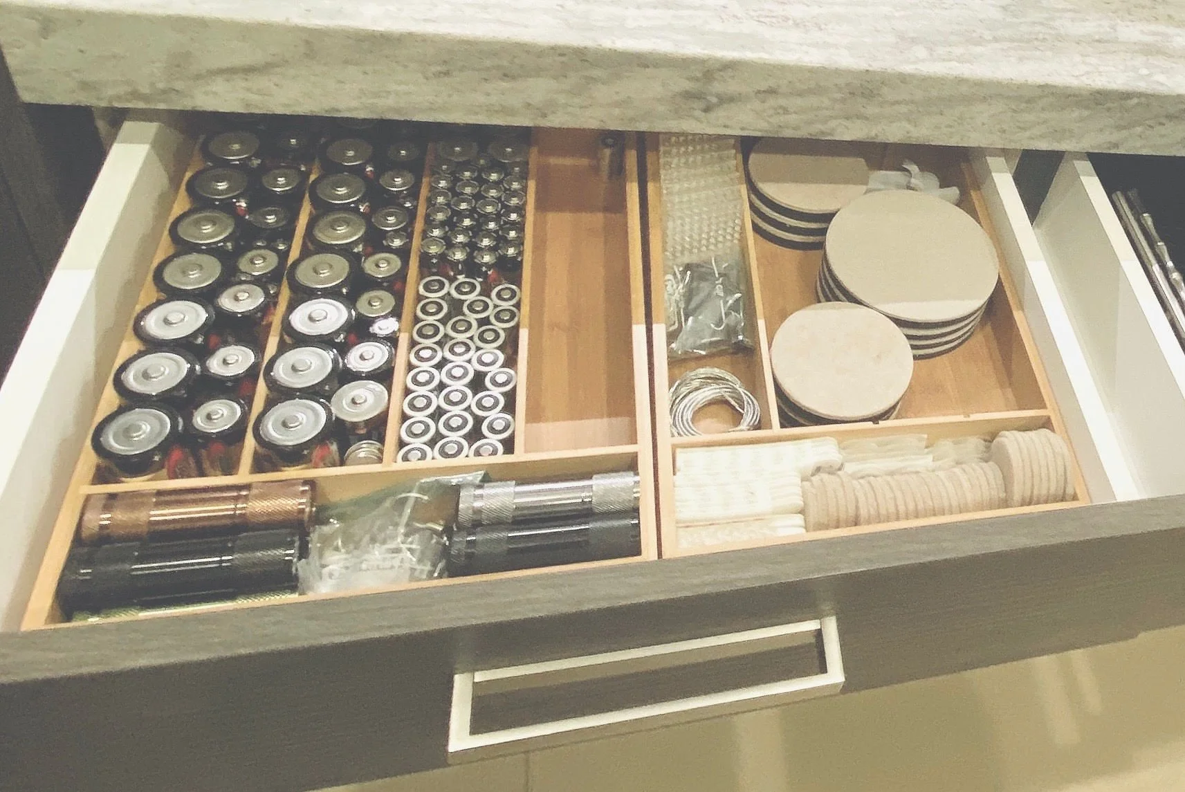 Perfectly sorted home utility drawer featuring designated sections for batteries, flashlights, furniture pads, movers, and art hanging hardware in Park City, Utah.