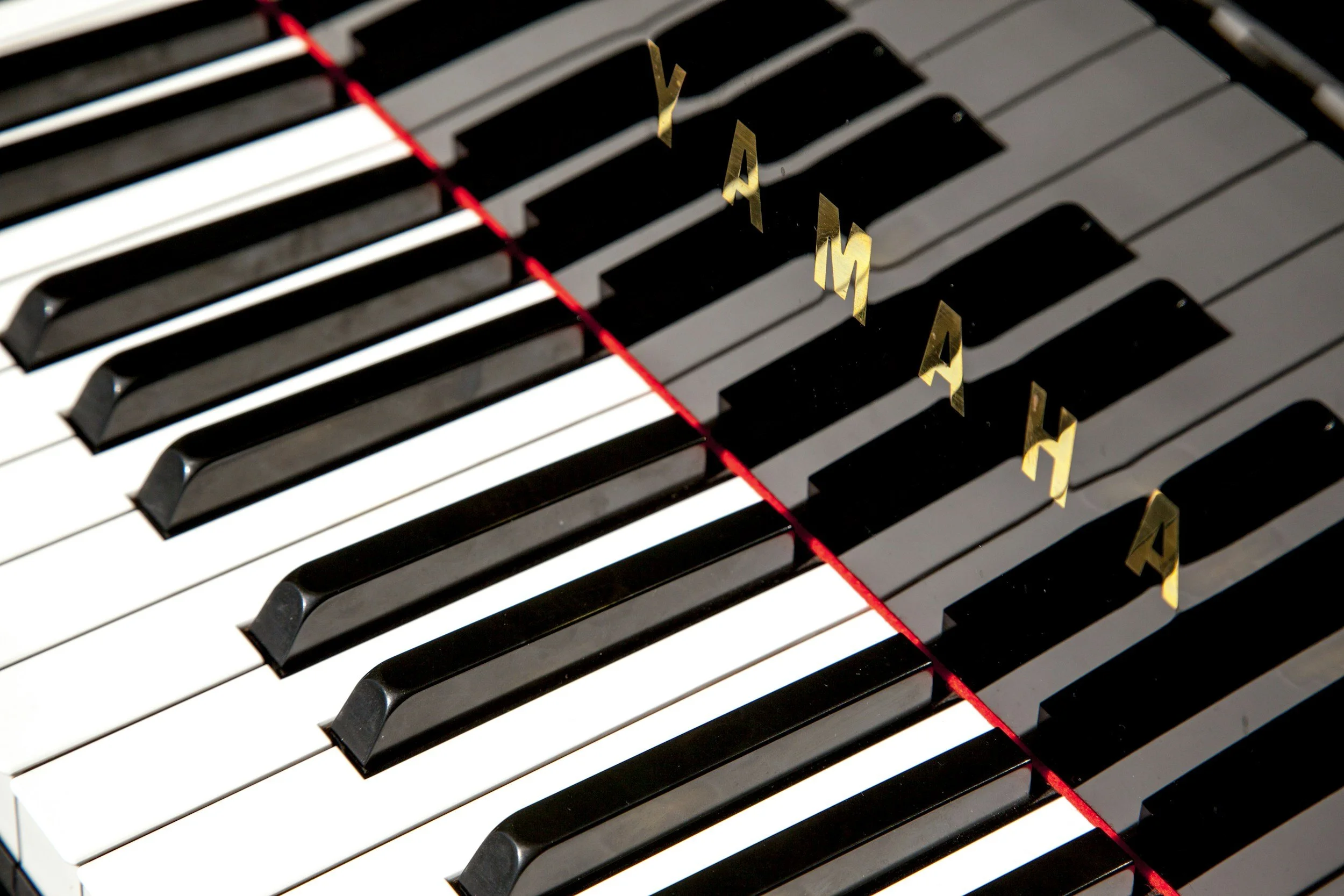 Close-up of piano keys with gold letter-shaped markers on some black keys.