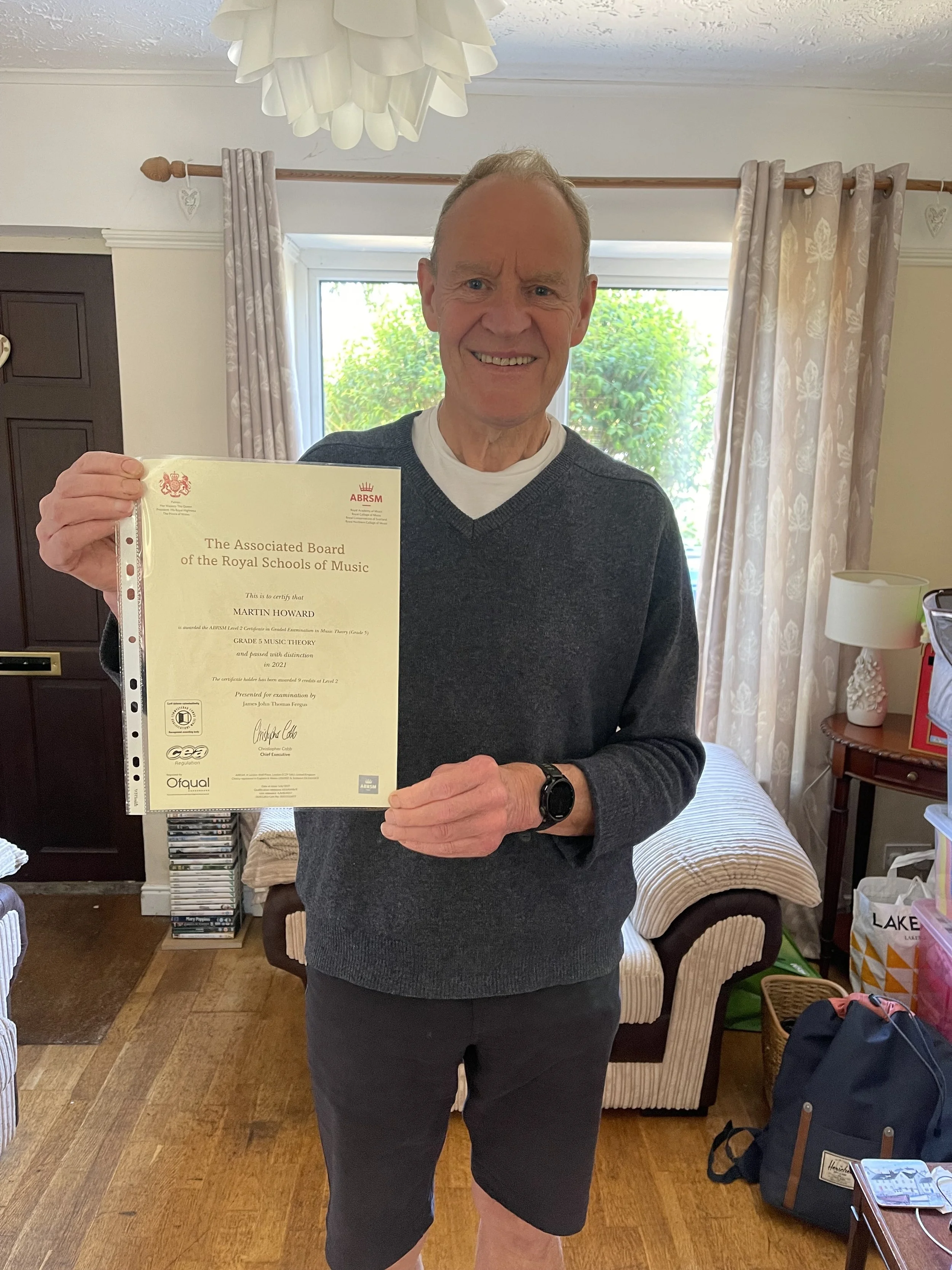 A man proudly holding his Music certificate 