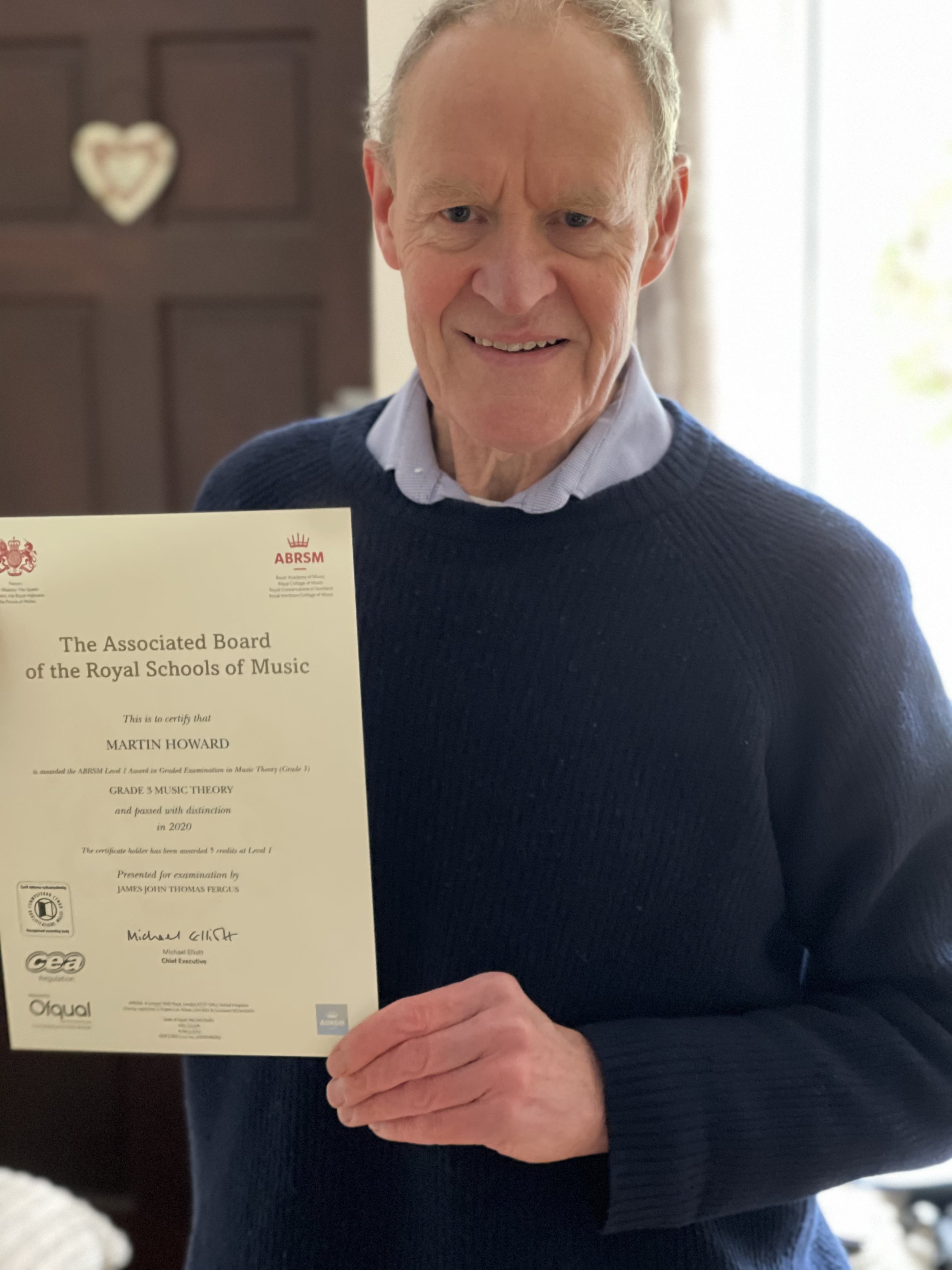A man proudly holding his Music certificate 