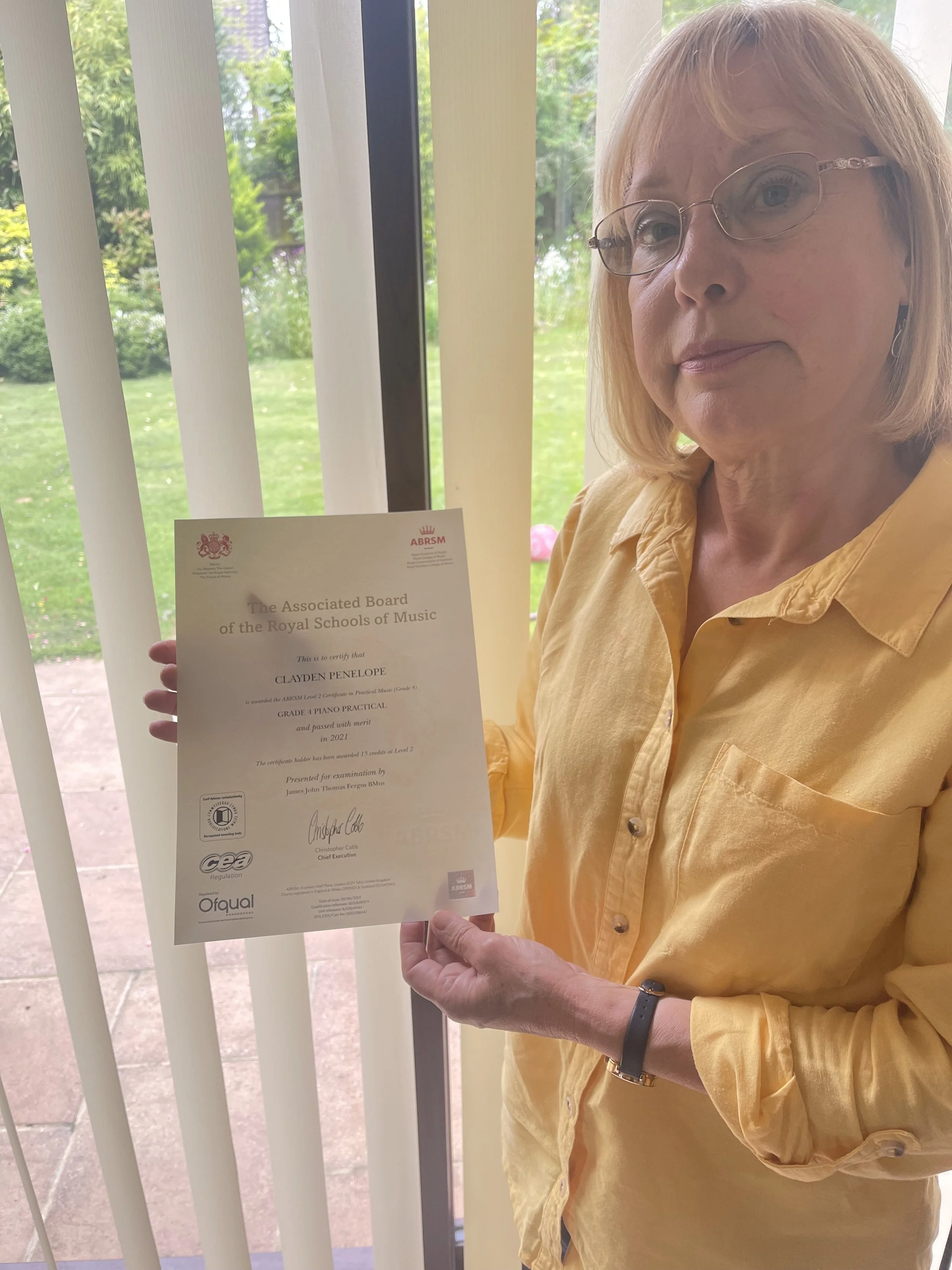 A woman proudly showing her music certificate