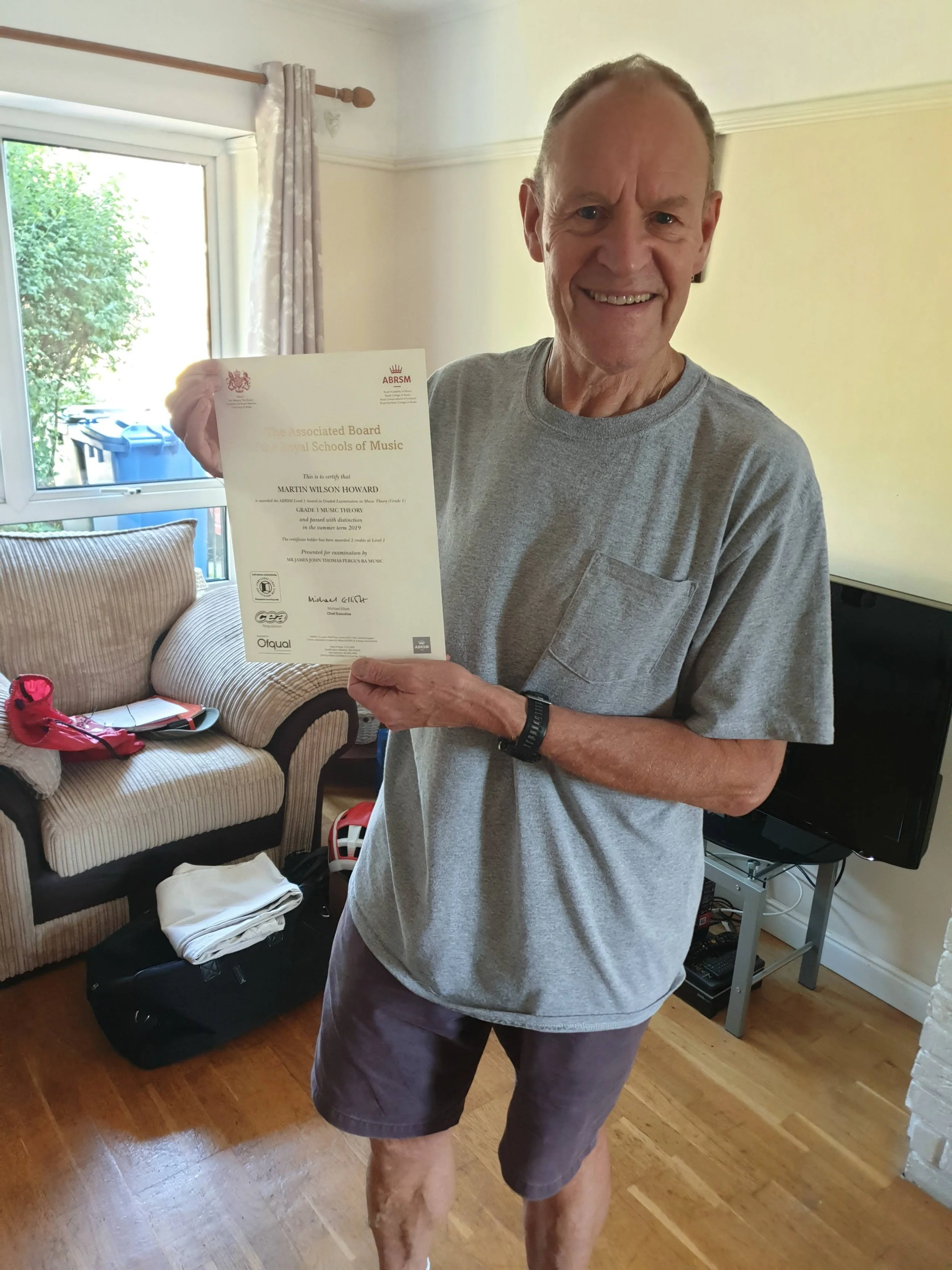 A man proudly holding his Music certificate 