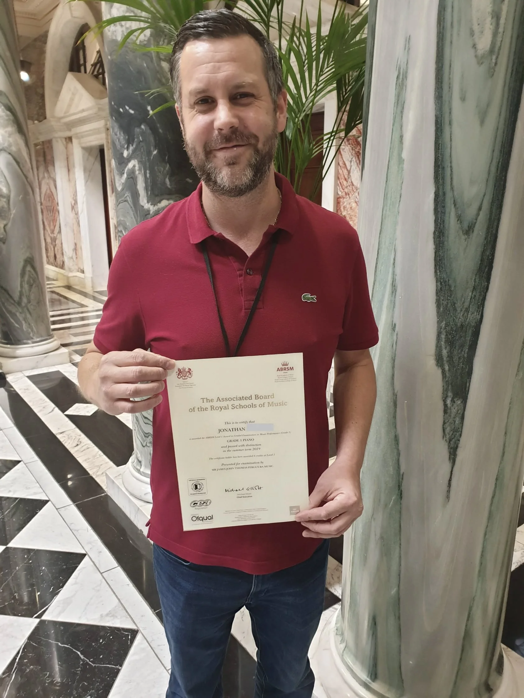 A man proudly holding his Music certificate 