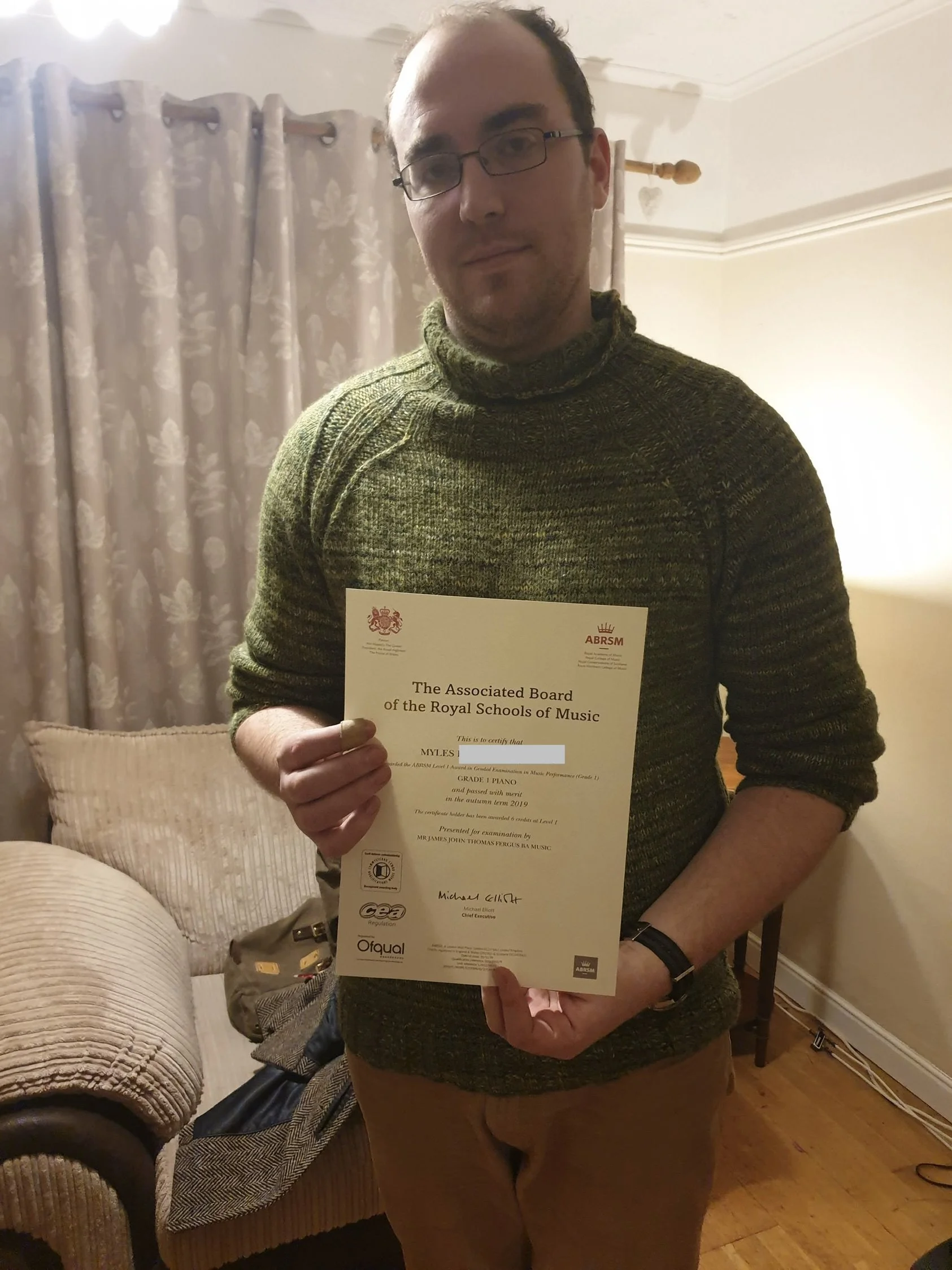 A man proudly holding his Music certificate 
