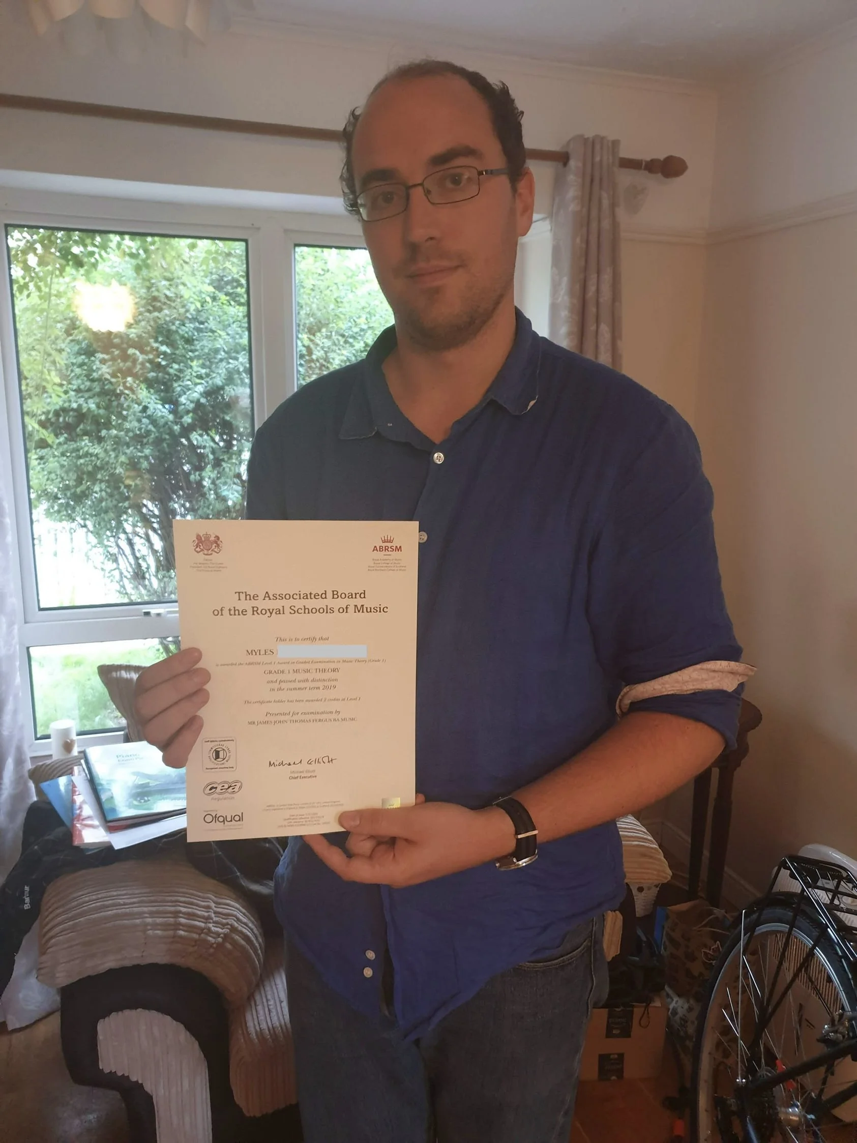 A man proudly holding his Music certificate 
