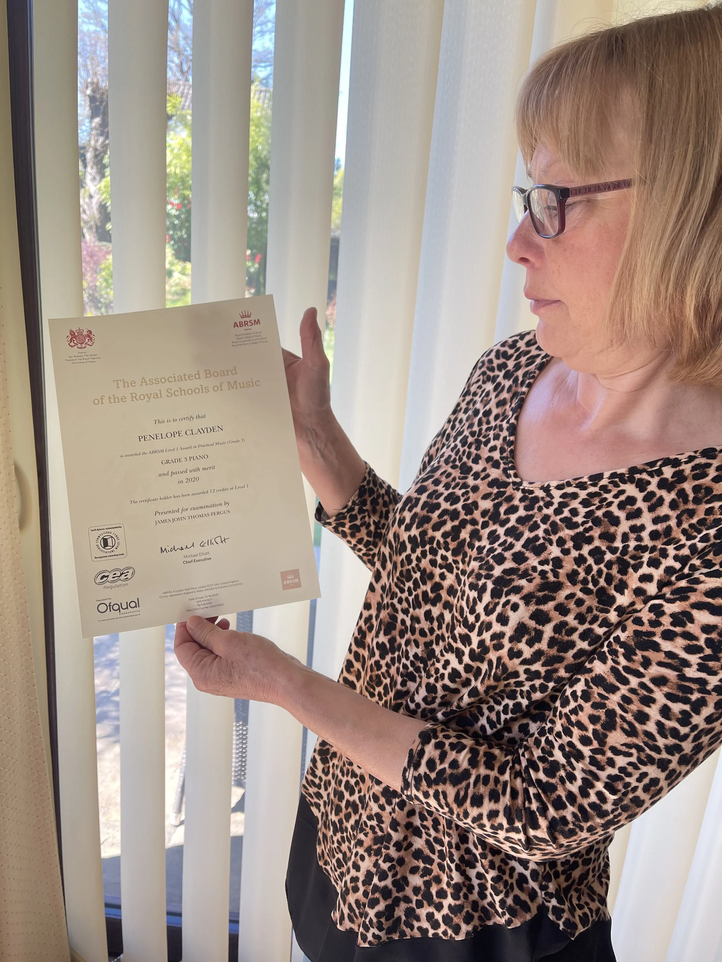 A woman proudly showing her music certificate