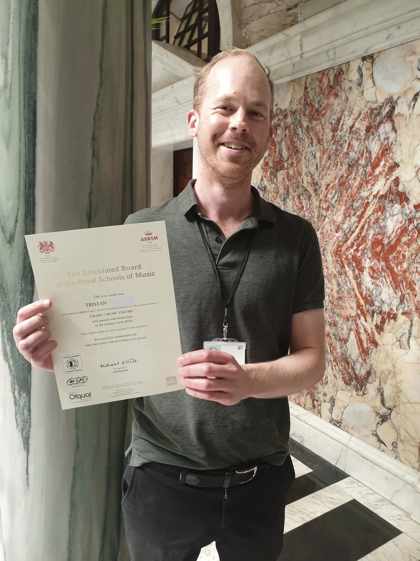 A man proudly holding his Music certificate 