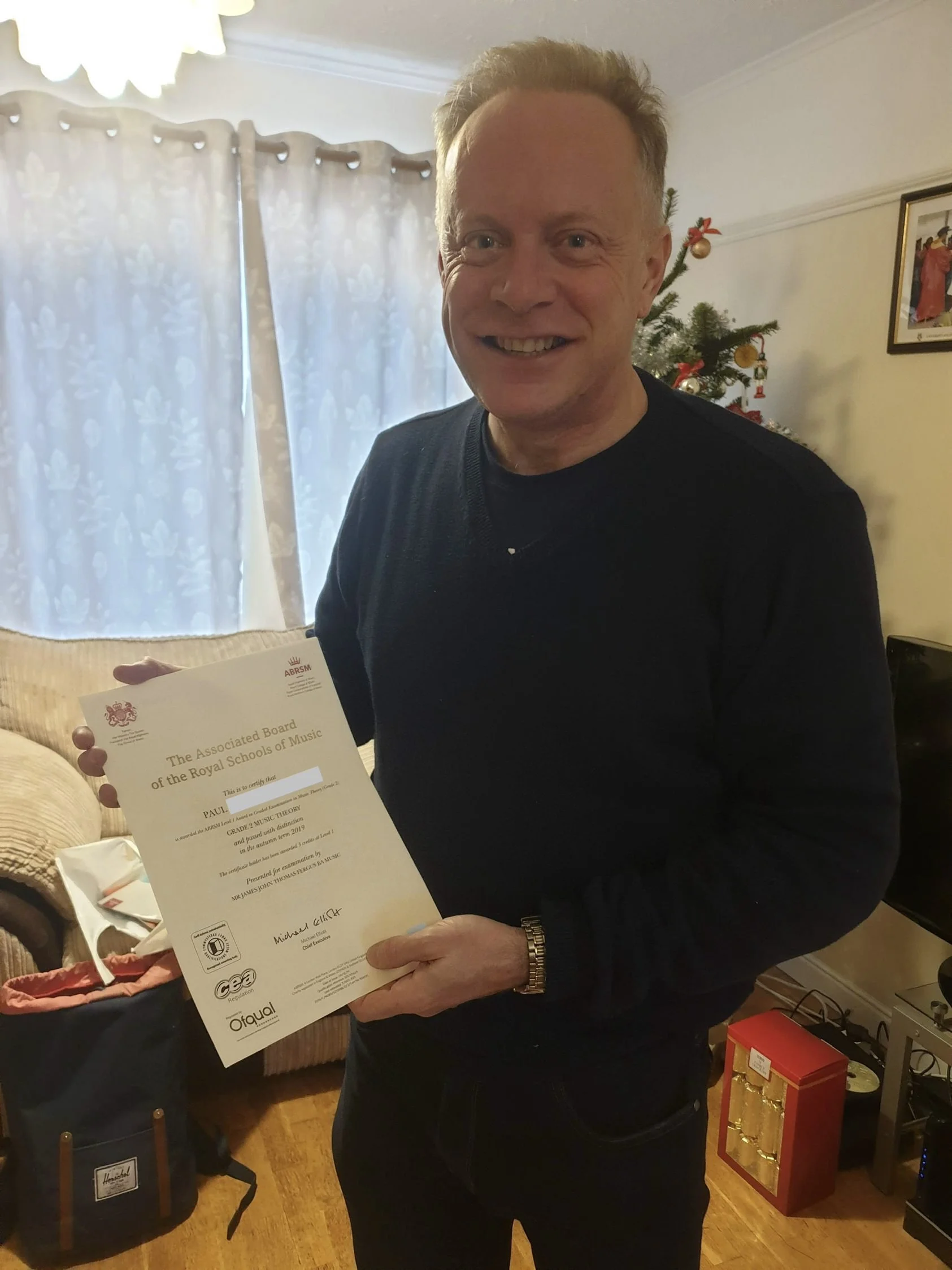A man proudly holding his Music certificate 