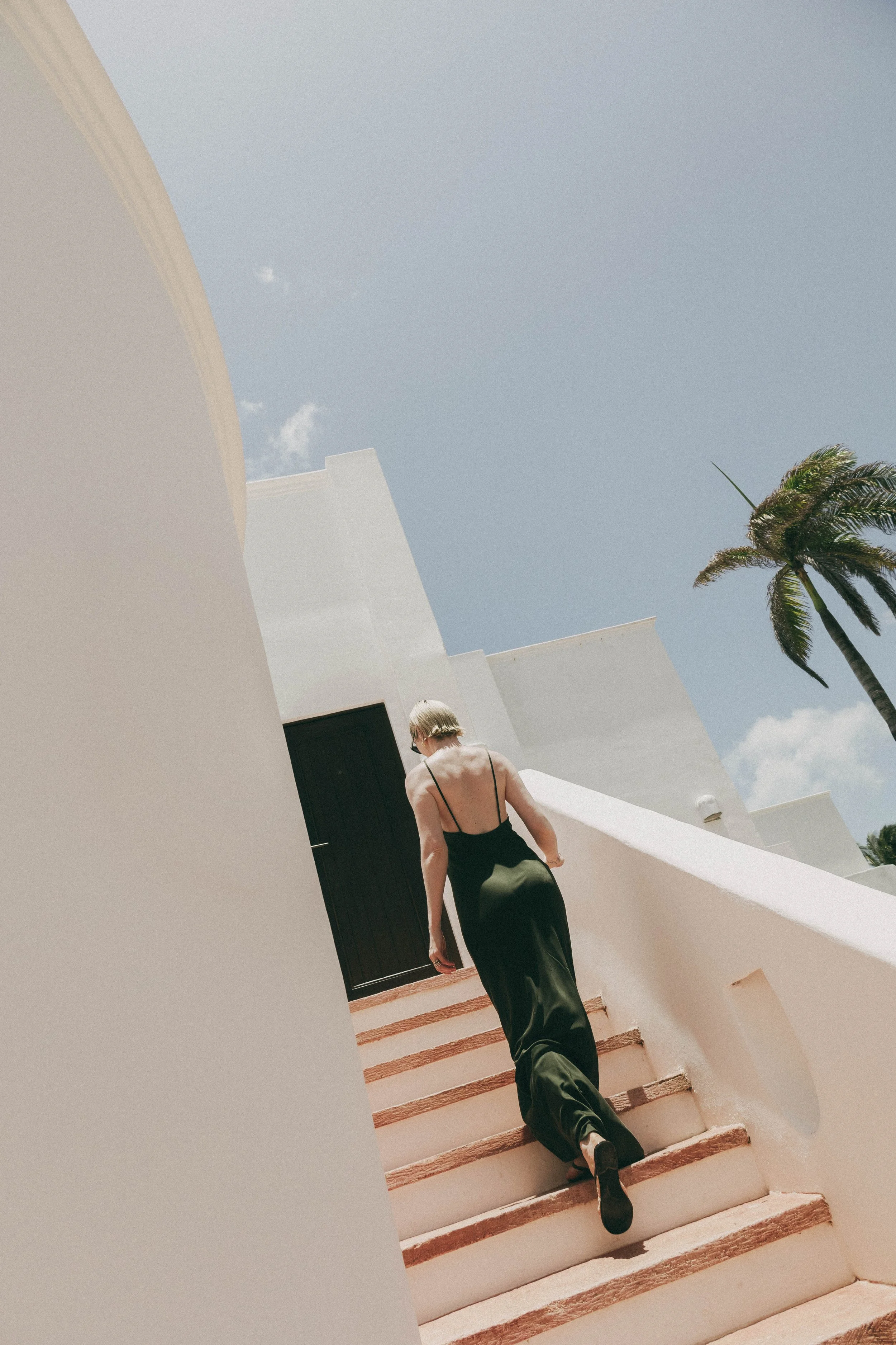 beautful women in minimal luxury dress walking up the stairs of luxury hotel