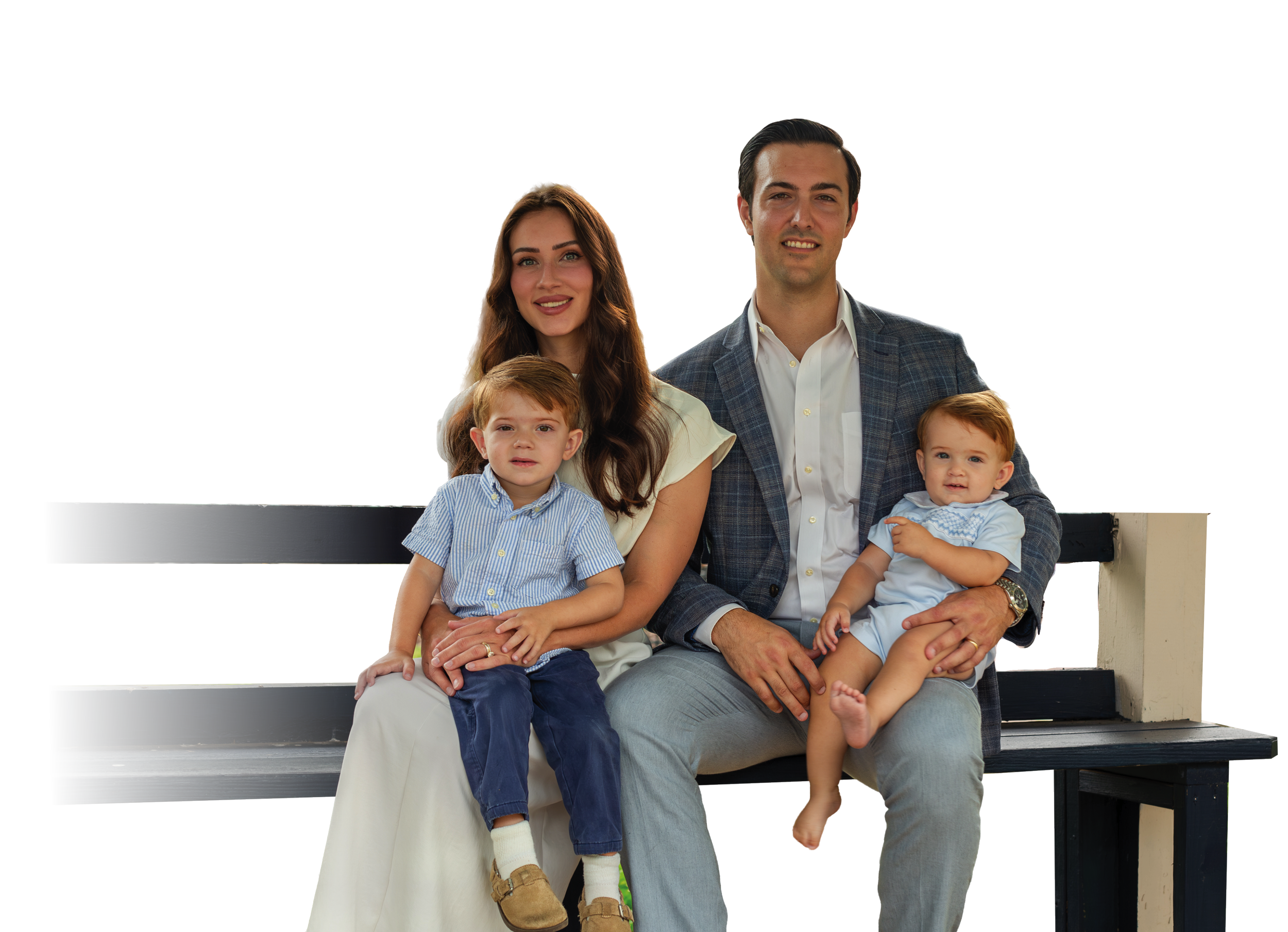 Garrett Greco and family sitting on black wooden park benches outdoors.