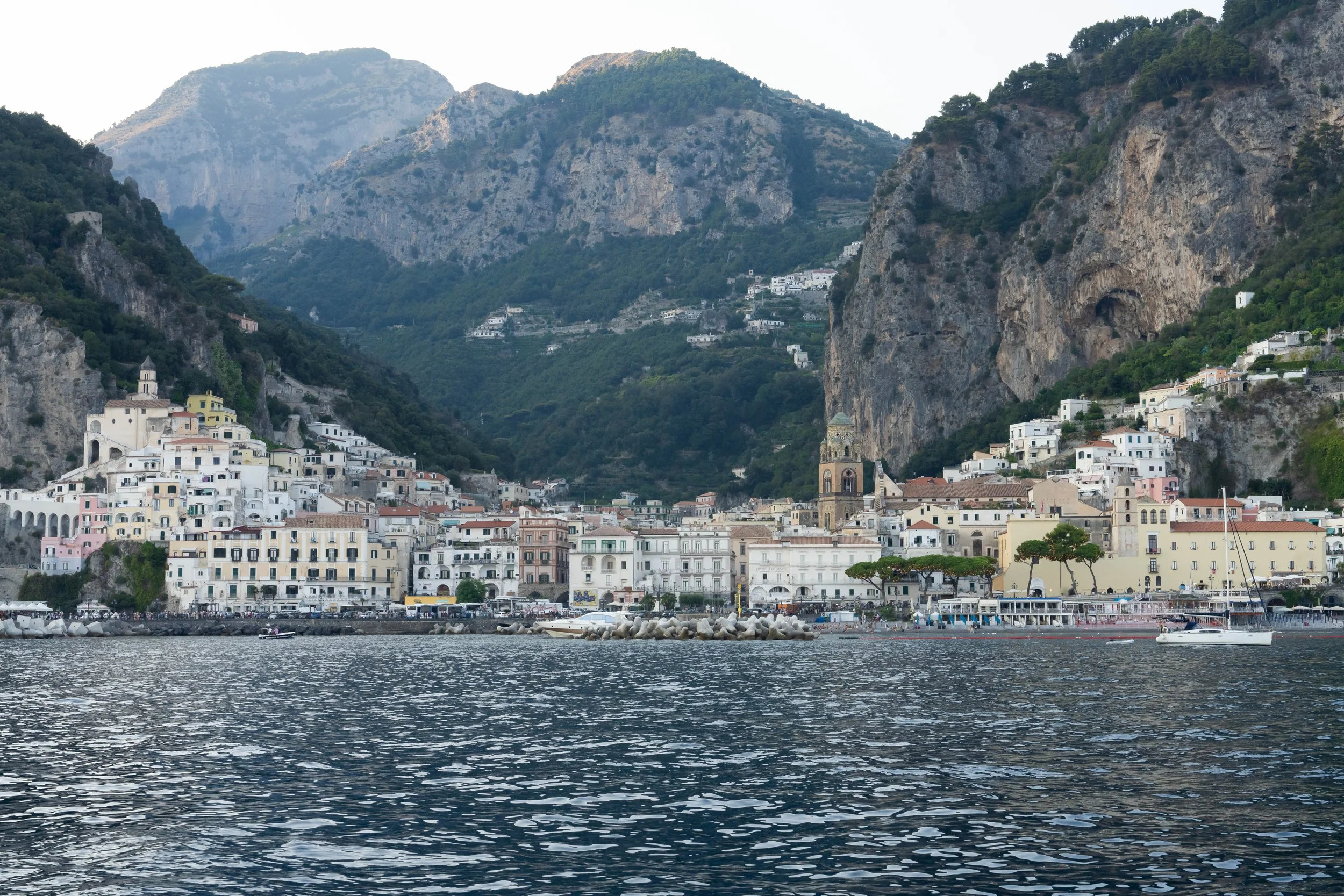 Amalfi, Italy with colorful buildings on hillside, mountains in background, and water in foreground.