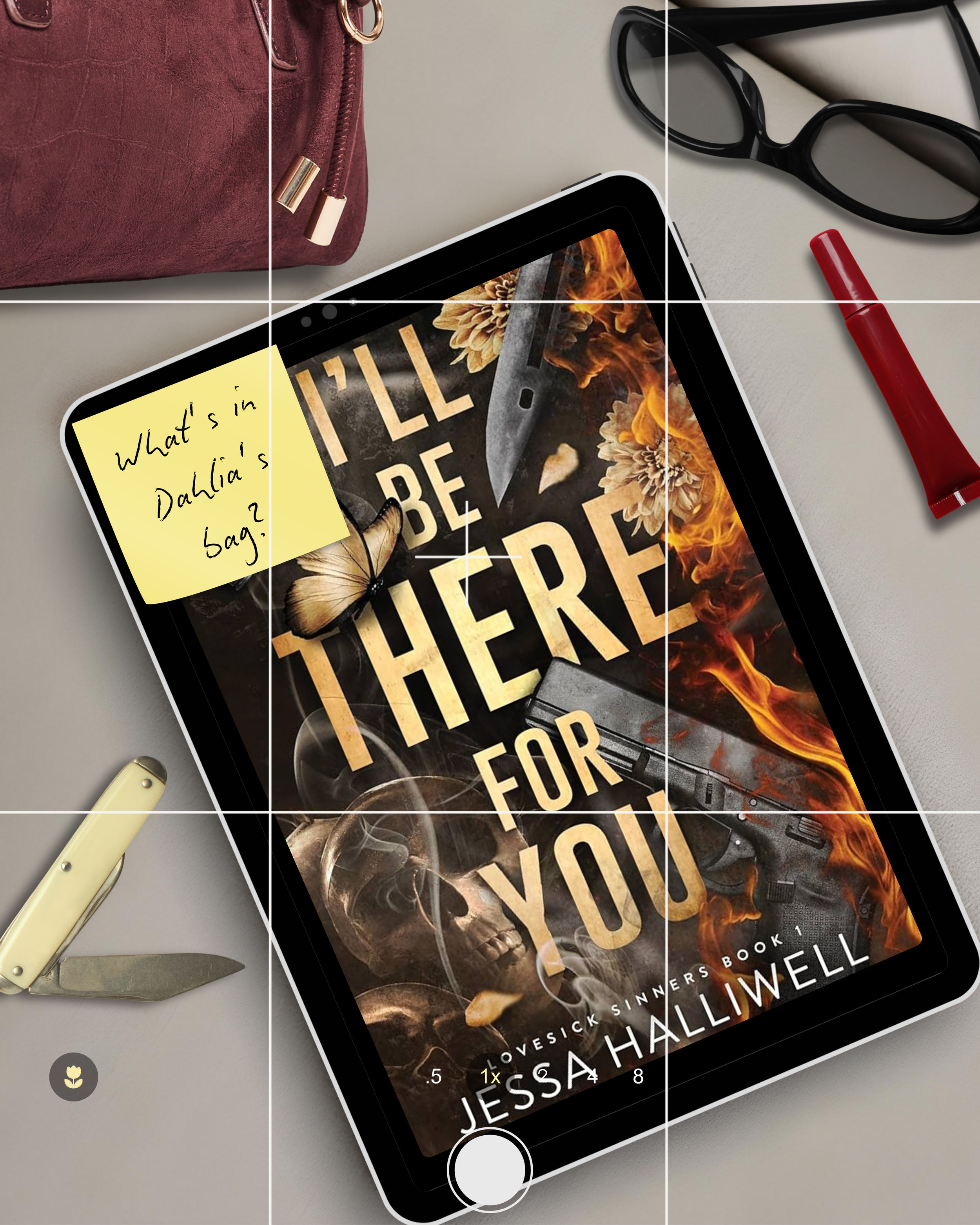 Close-up of a smartphone displaying the cover of the book "I'll Be Gone in the Dark" by Michelle McNamara, with a ring light reflection on the screen. Surrounding items include a pair of black sunglasses, a red lipstick, a manual silver and black uti