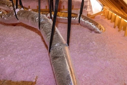 Fiberglass insulation in an attic with HVAC ductwork shown.