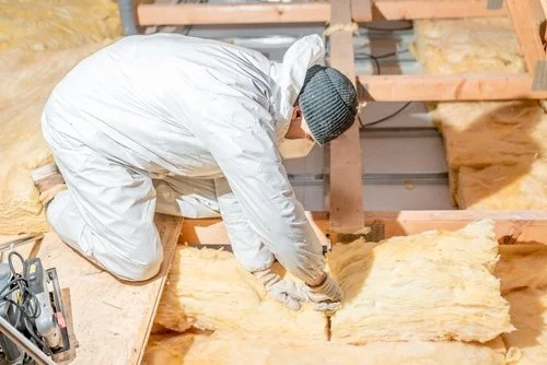 Man in white protective suite installing insulation.