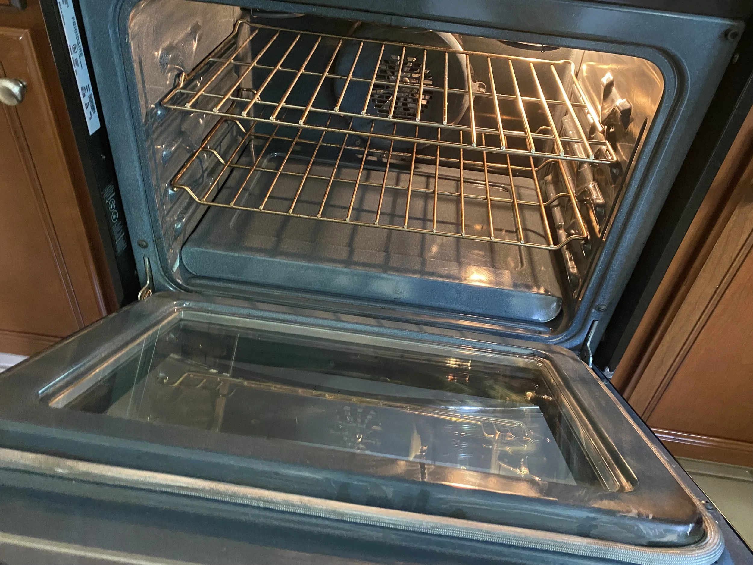 An open oven with two empty wire racks inside and a heating element at the top.