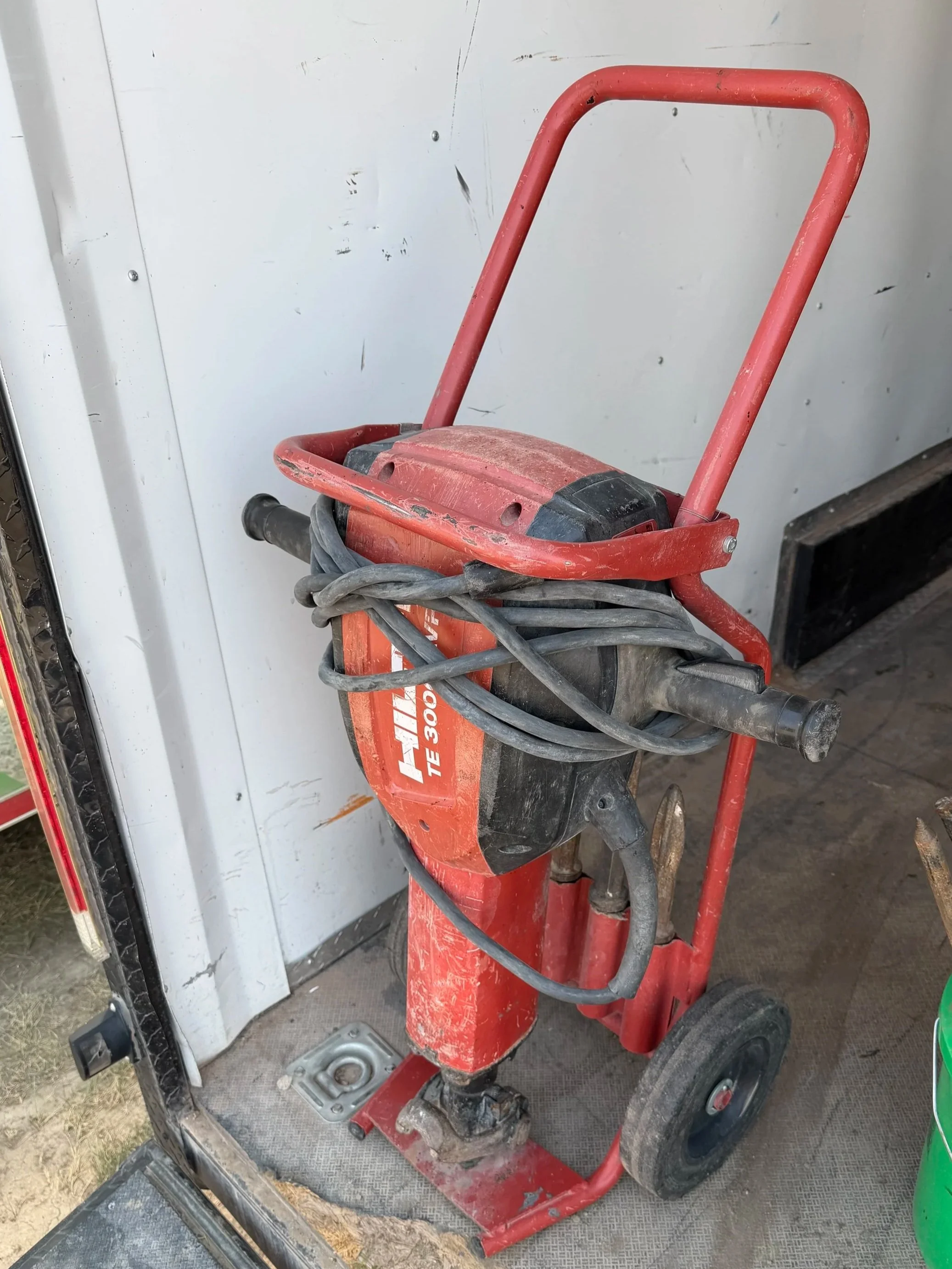 Red power tool cart with black cables on a gray textured surface