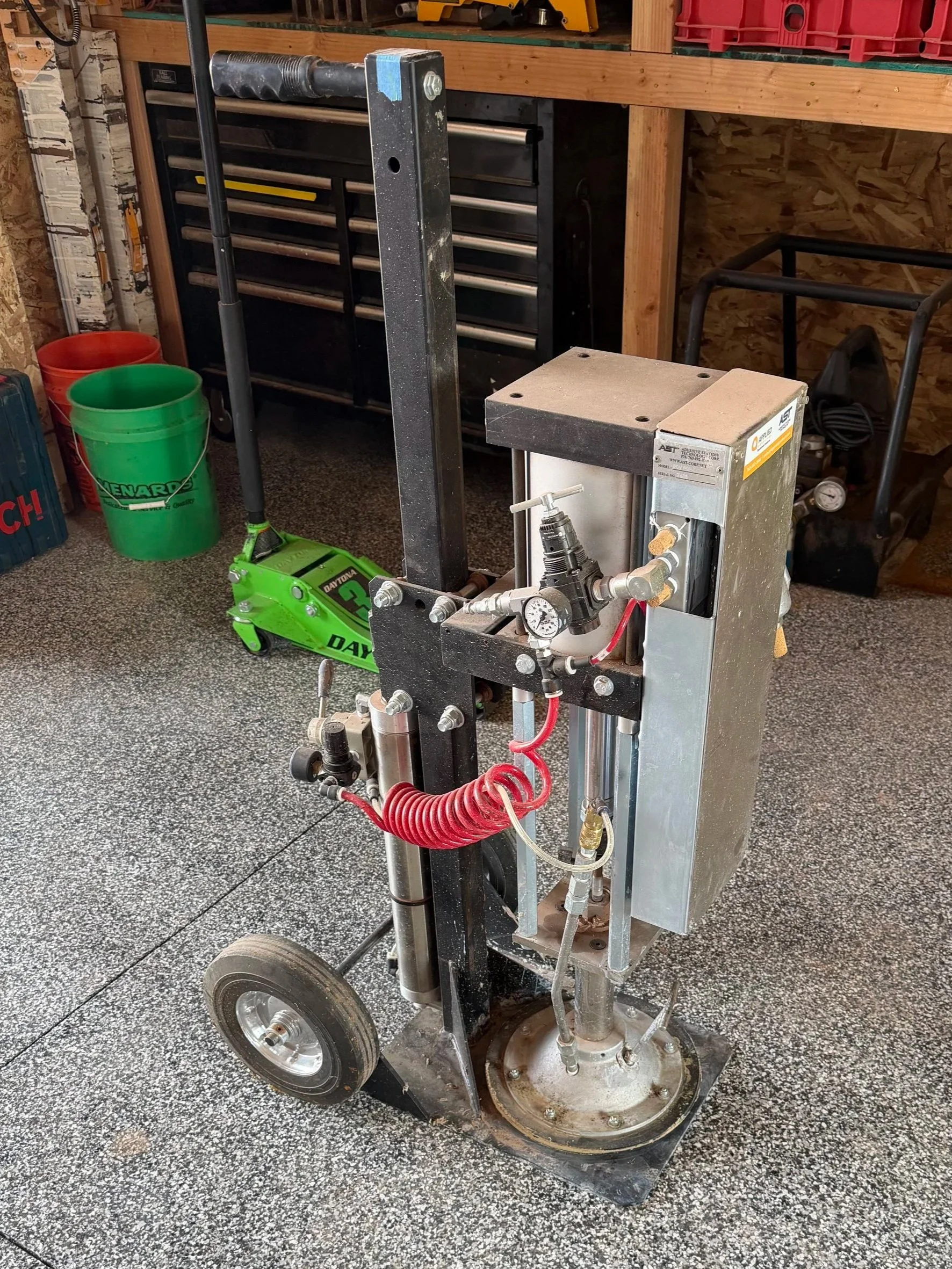A mobile workshop drill press or milling machine in a garage or workshop setting.