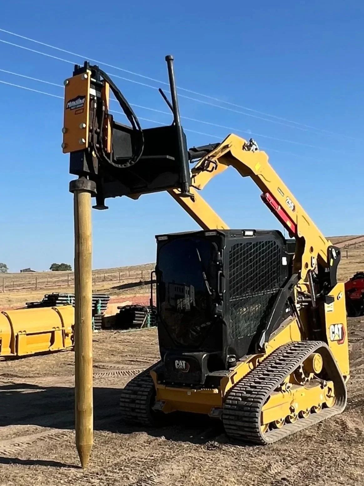 A yellow and black construction machine on dirt with a handle and cables.