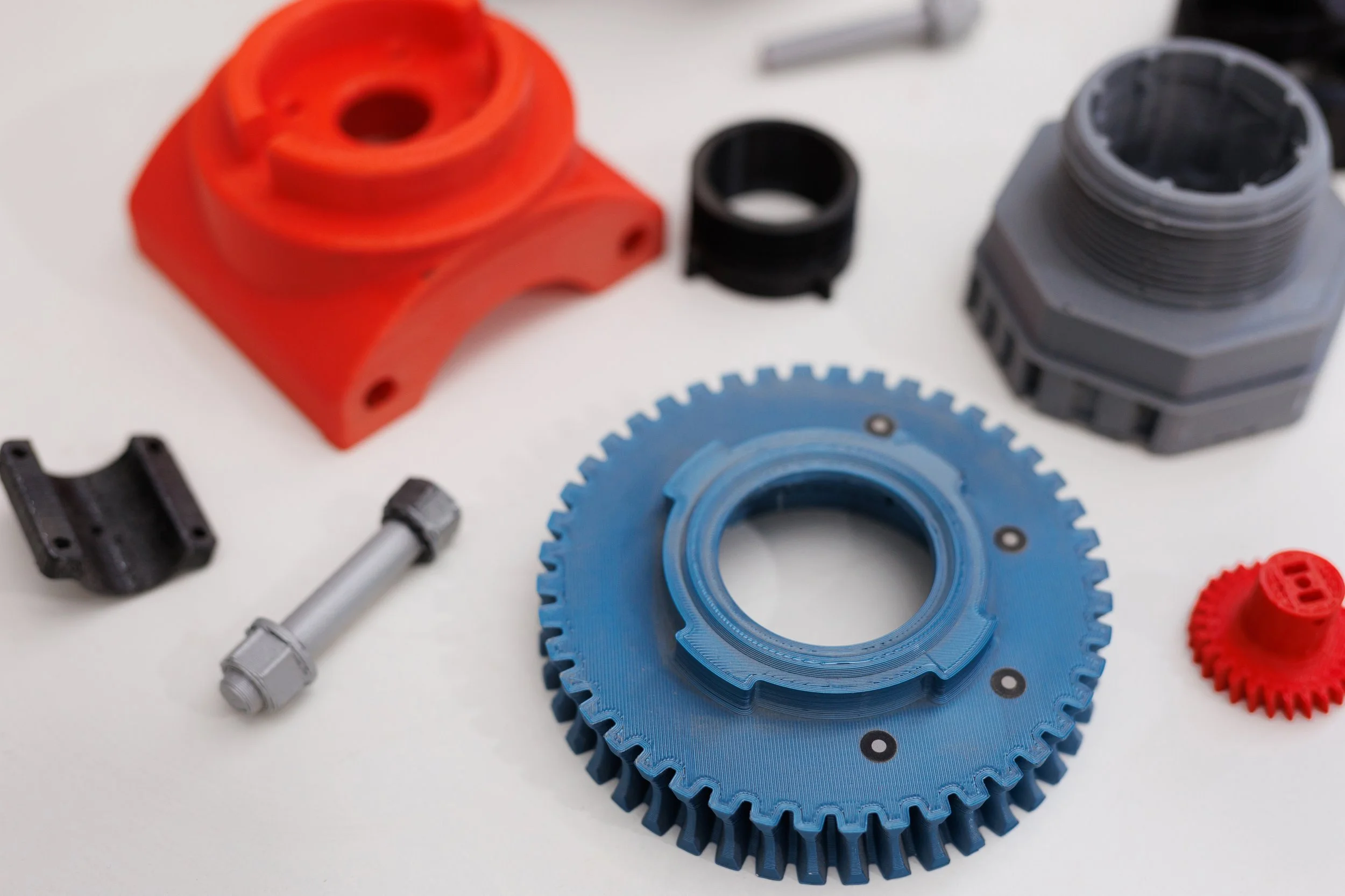 Set of mechanical parts including gears, bushings, and a housing component, arranged on a white surface.