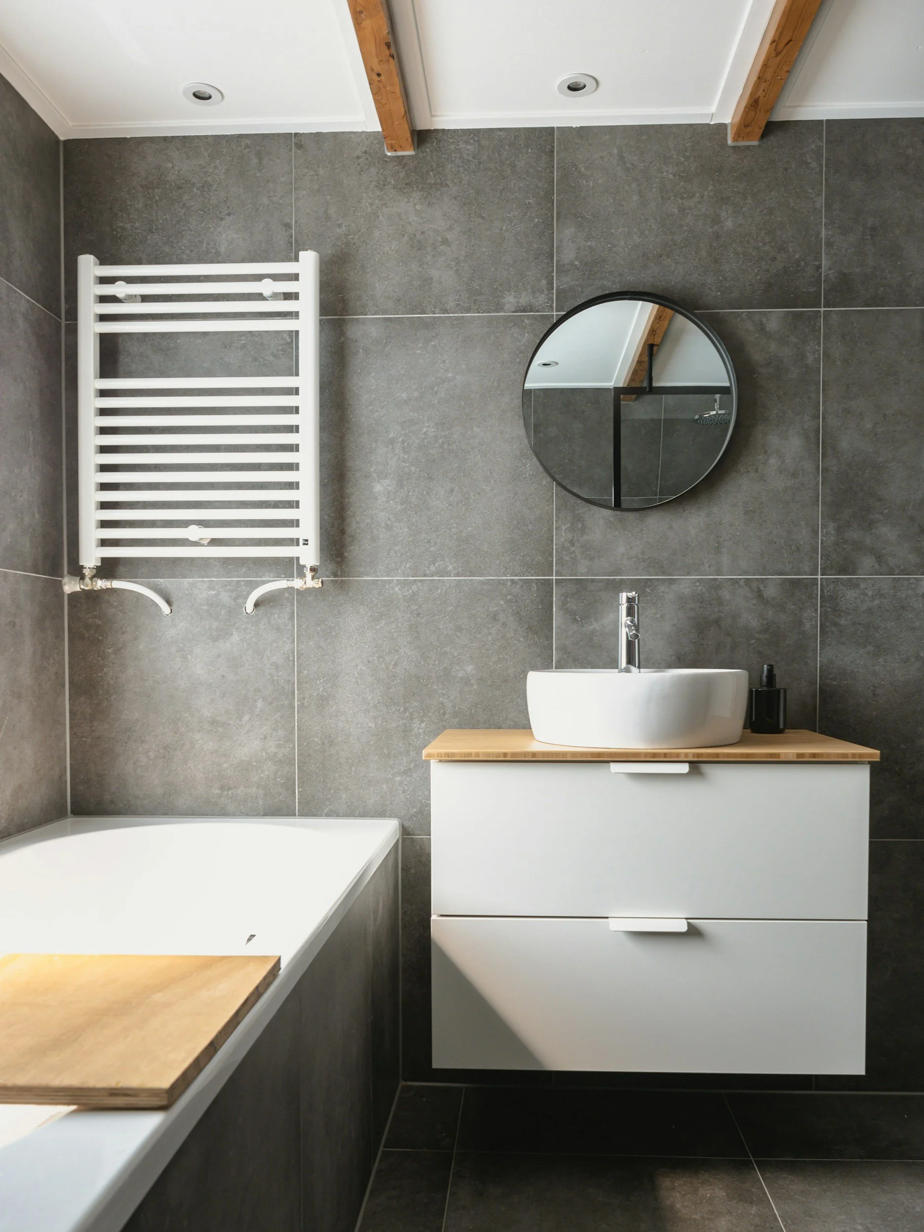 Clean and shiny modern bathroom with grey tiled walls and a white vessel sink, cleaned by Cheltenham Cleaning Company