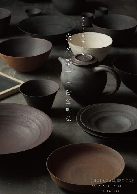 Various dark-colored ceramic bowls, plates, and a teapot arranged on a surface with Japanese text overlay and a logo indicating a gallery event from July 7 to July 16, 2017.