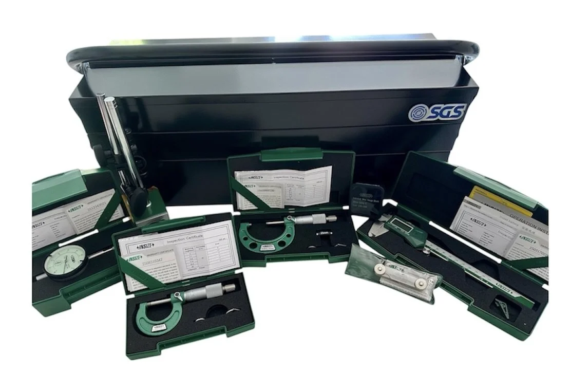 A set of green and black inspection tools and documents for quality control, including a micrometer, dial gauge, and calibration certificates, organized in cases and displayed in front of a large black storage box.