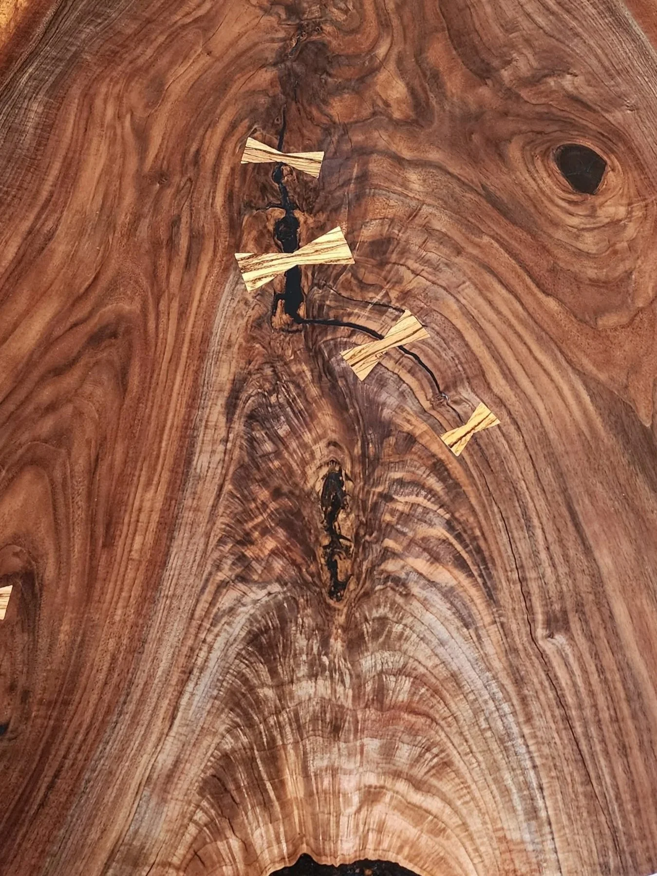 An image of black walnut crotch feathering and curl with black epoxy and zebrawood bowtie inlays