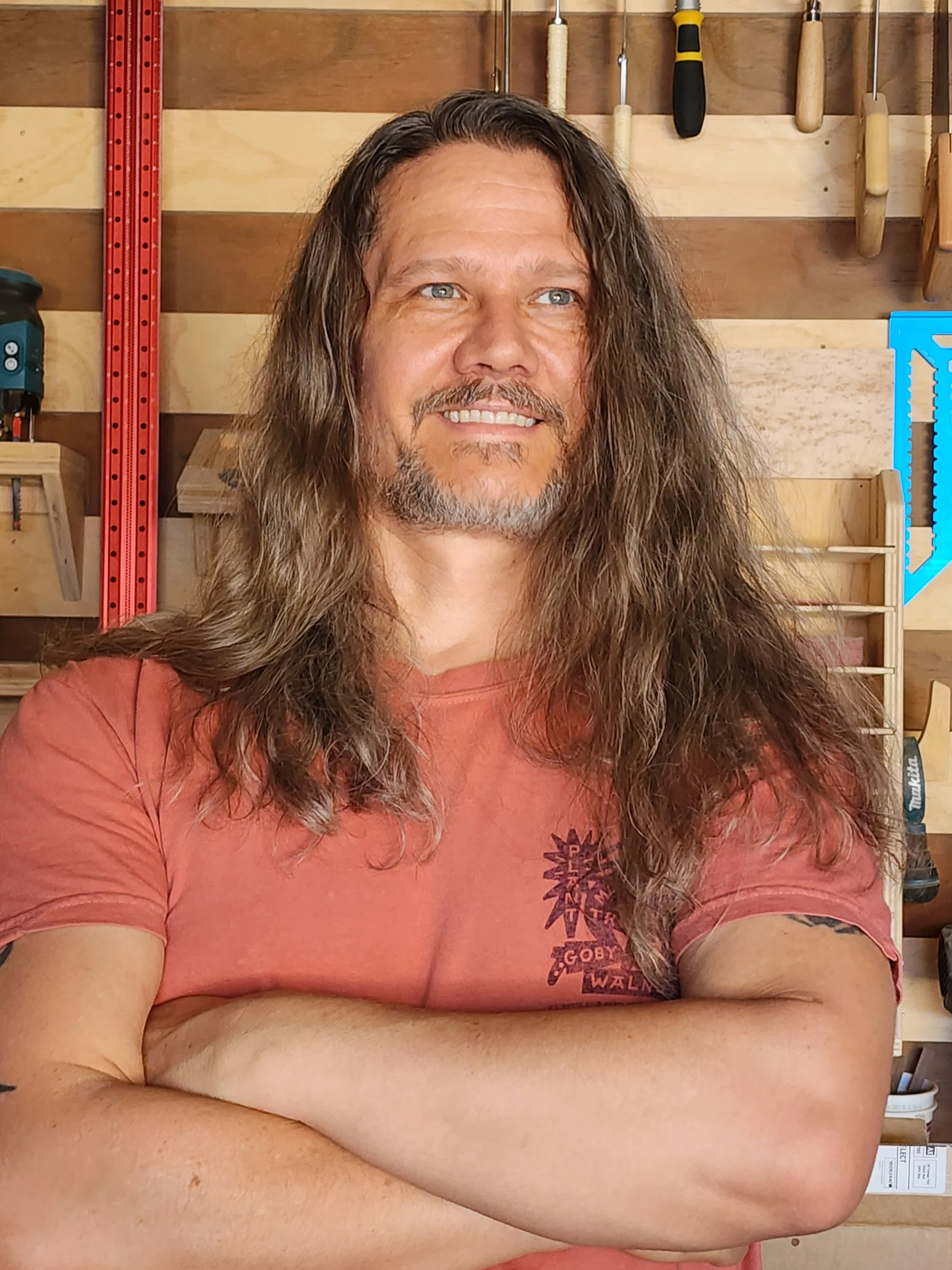 Woodworker Adam Armistead standing in front of the french cleat tool wall in his shop.