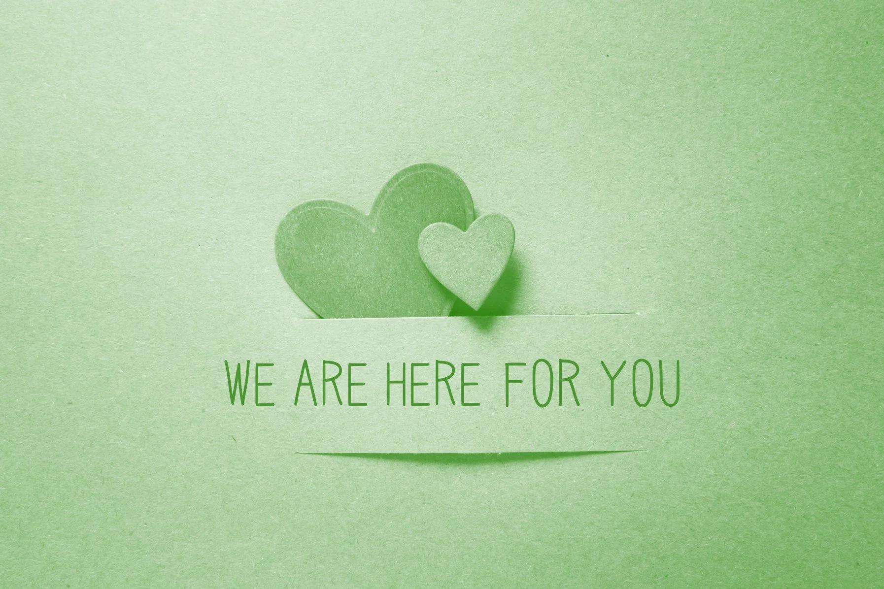Light green card illustration with two layered paper hearts and the words 'WE ARE HERE FOR YOU' in green text.