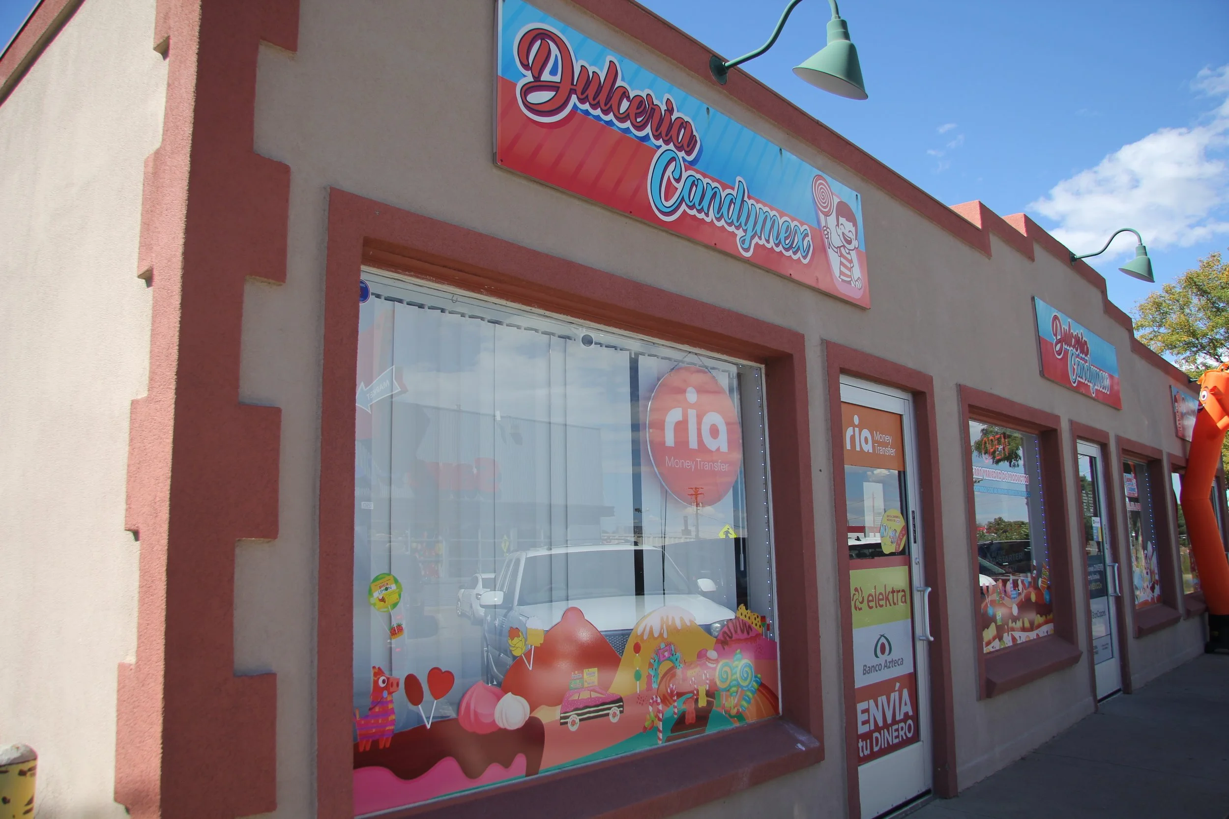 Exterior of a candy store called Dulceria Candymex with colorful signage and window display featuring candies and sweets.