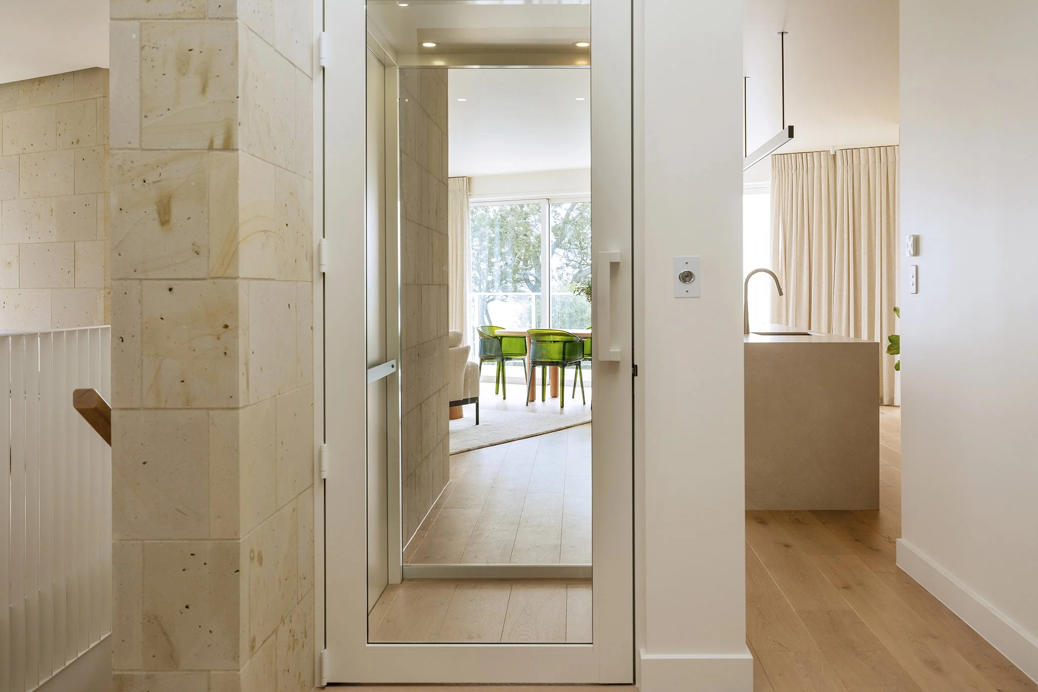 Contemporary home looking through glass elevator to dining room beyond